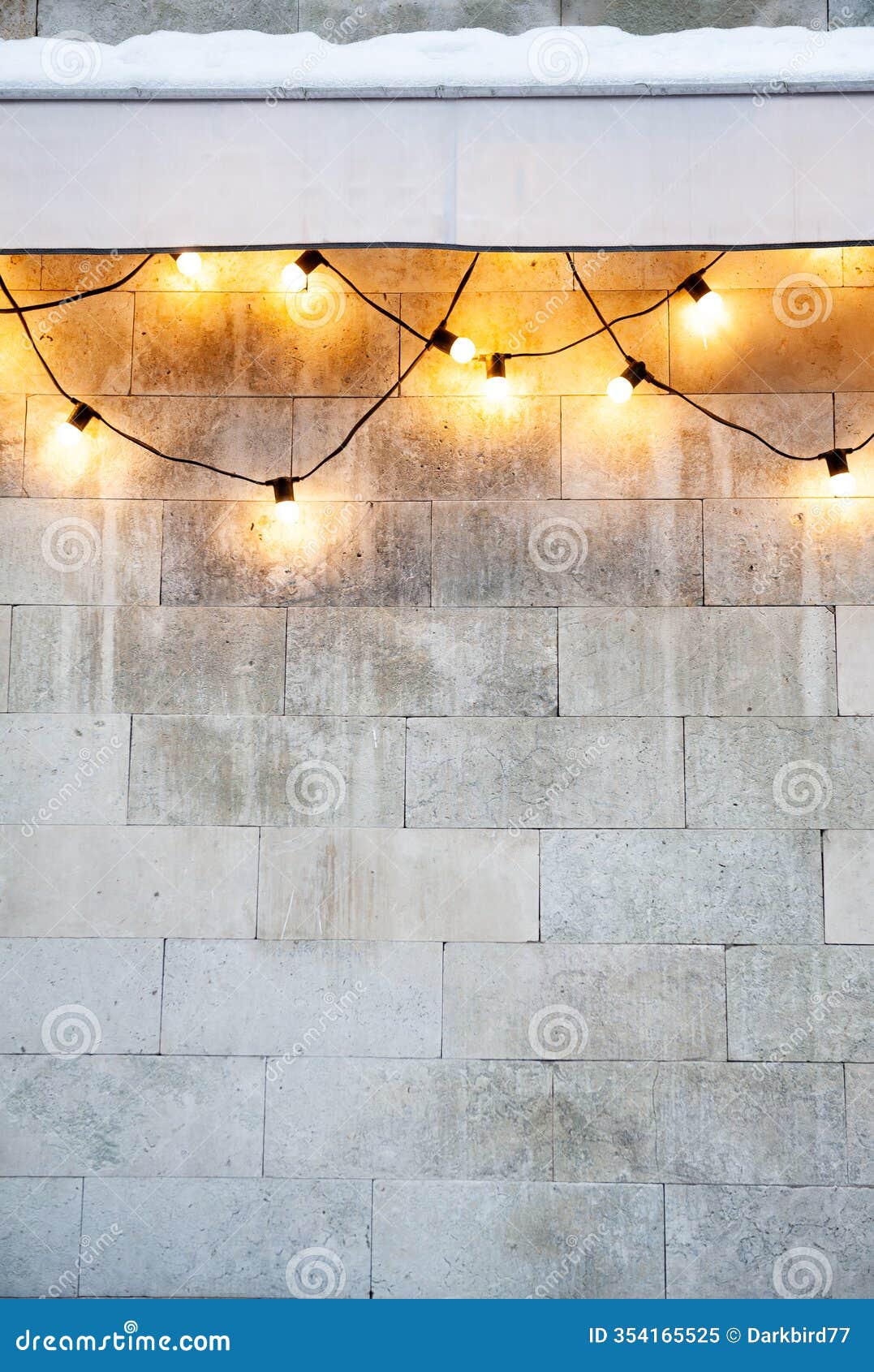 string lights glowing on a stone wall create festive outdoor holiday decor