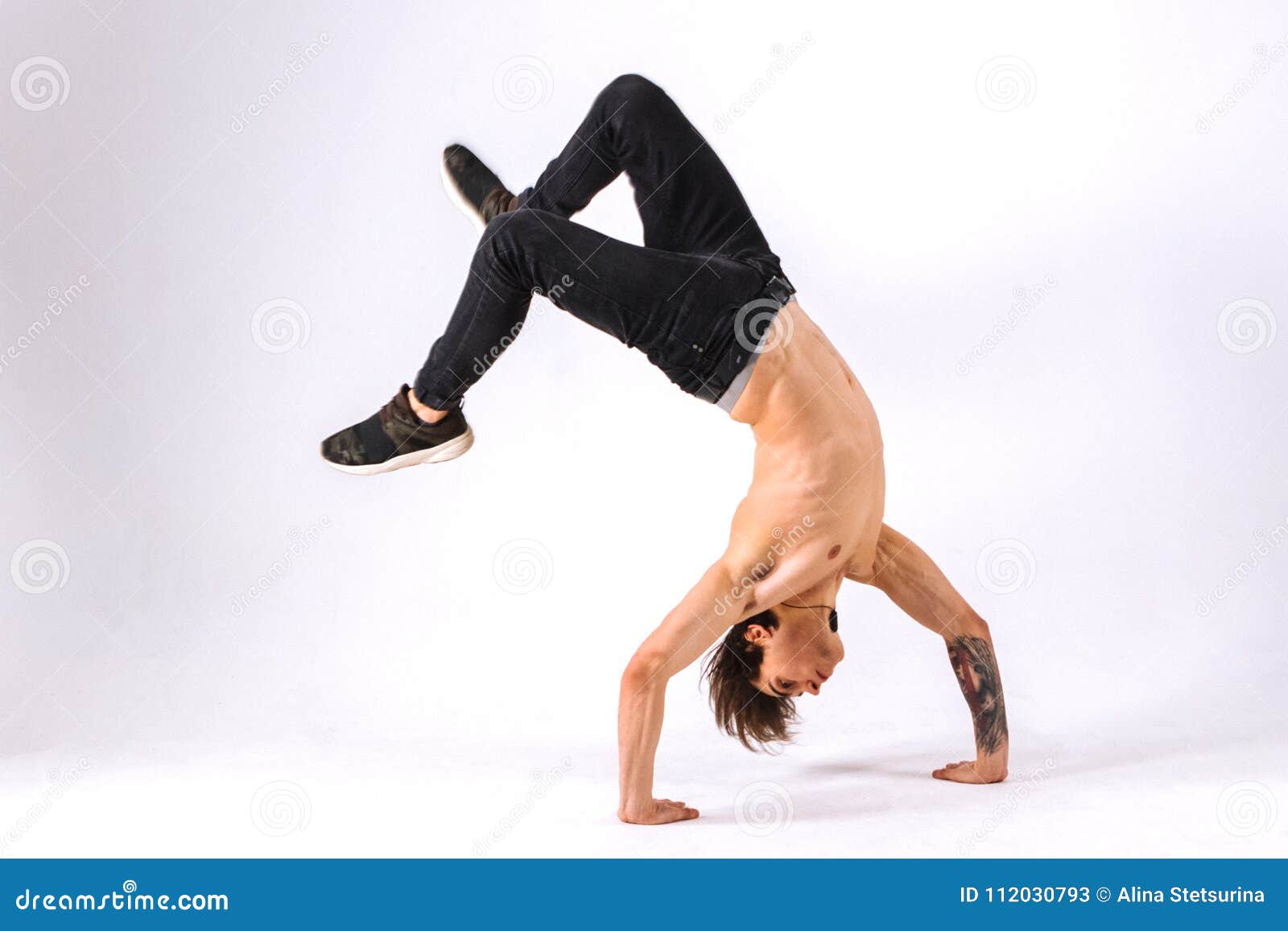 strong powerful boy, man - freerunner, acrobat, tricker with muscular body in a jump upside down on a white background