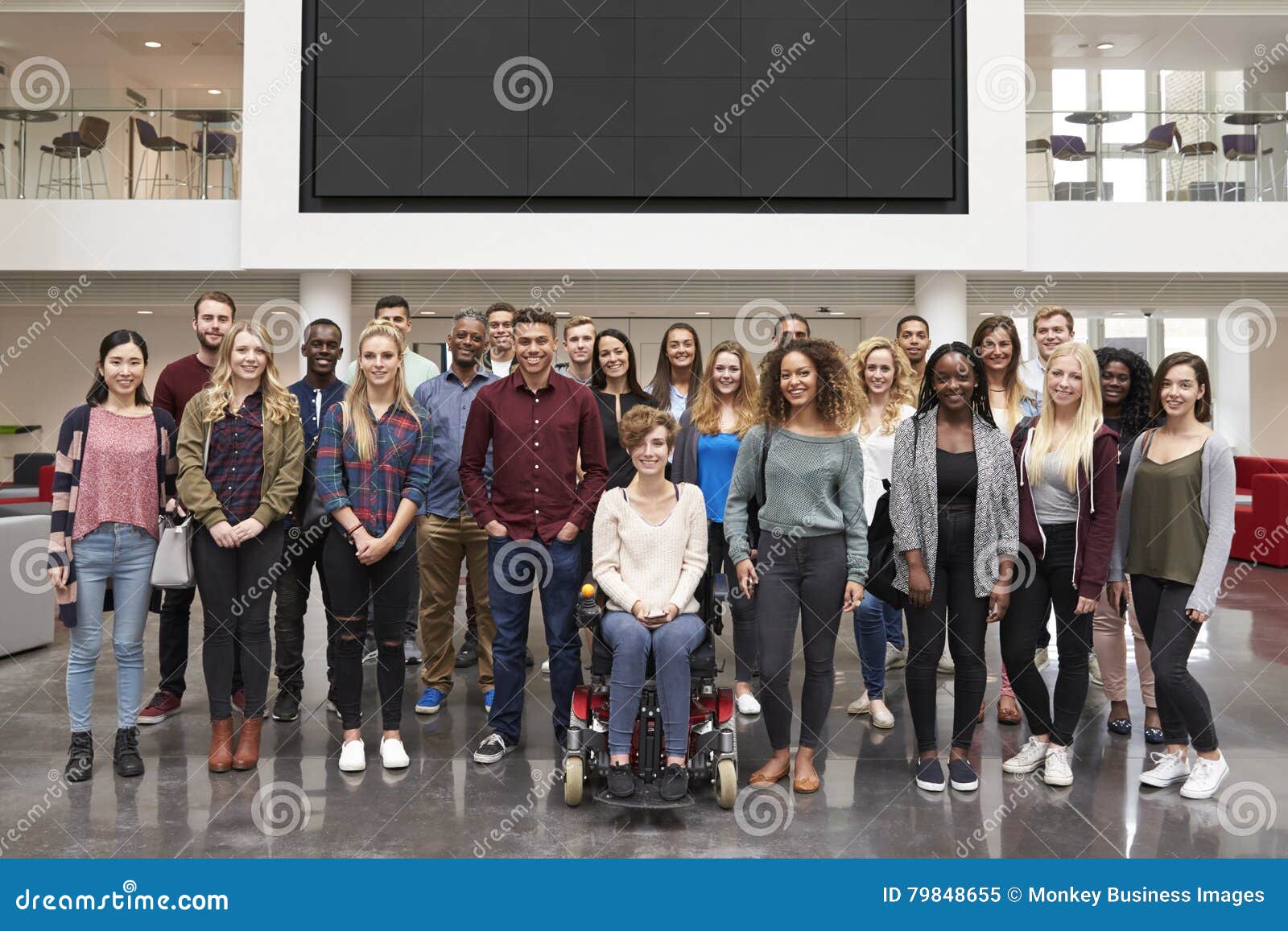 student group standing in atrium under a big av screen