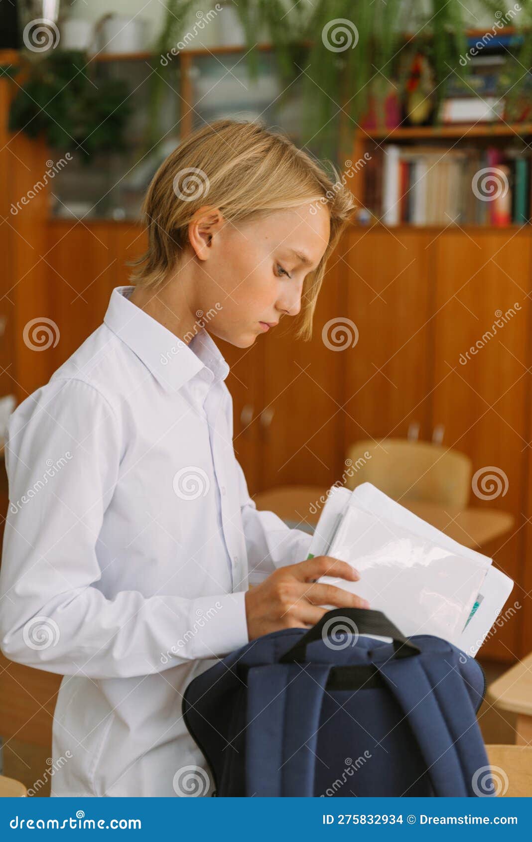 student put books in backback after lessons in classrom