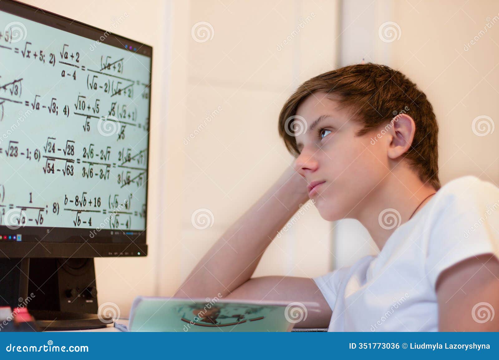 a student solves math problems on a computer. a teenage boy is studying online