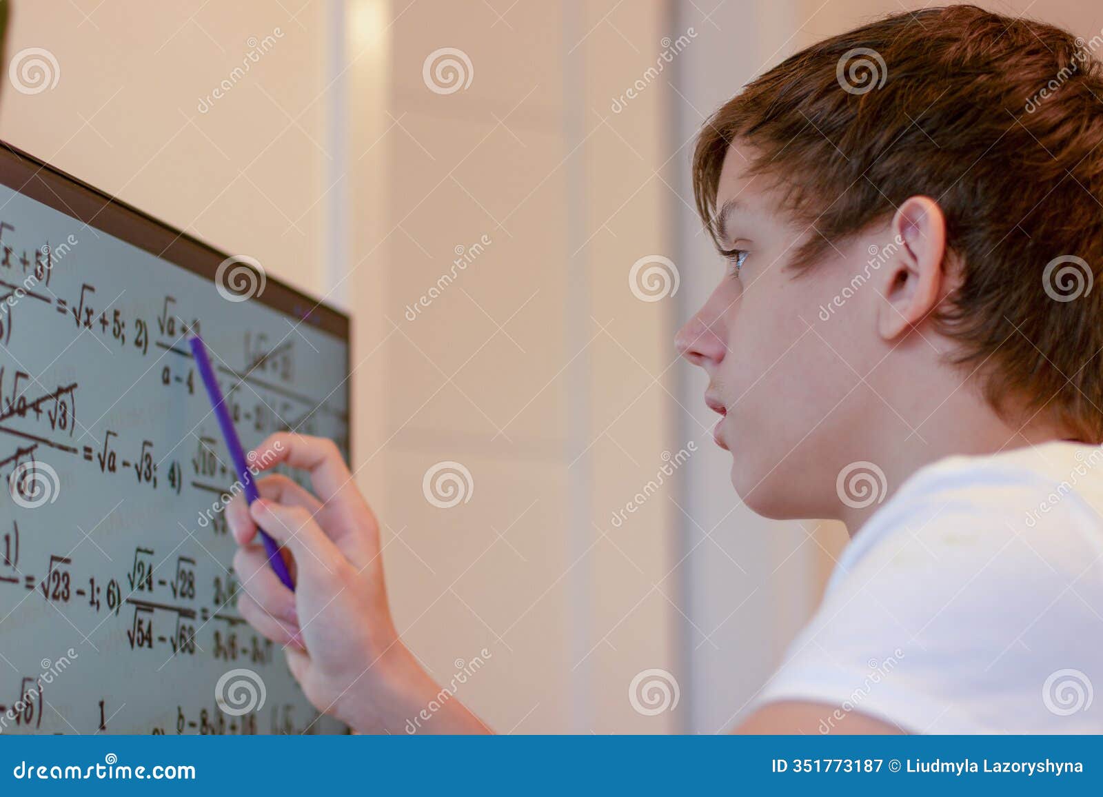 a student solves math problems on a computer. a teenage boy is studying online