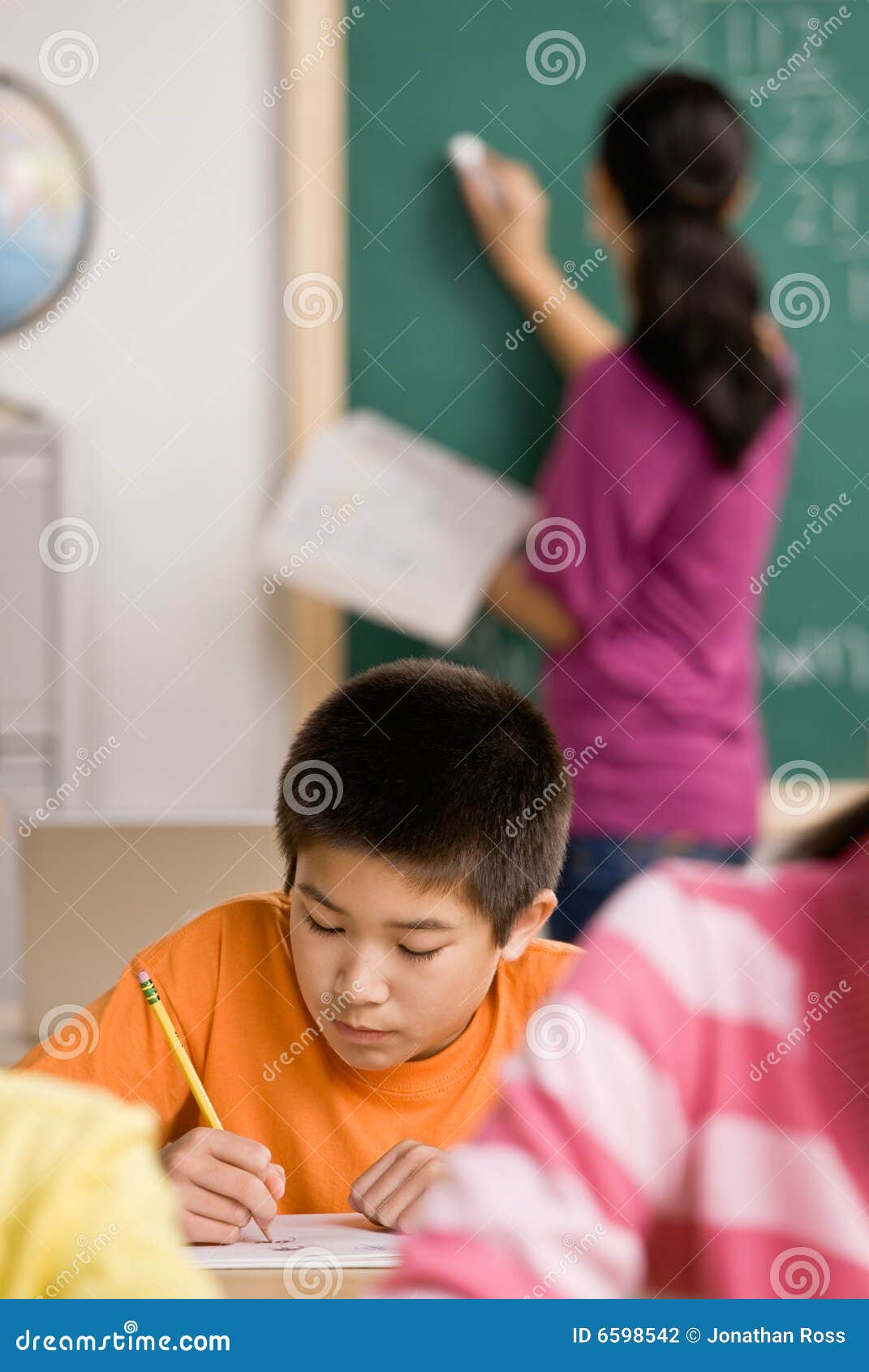 student writing in notebook in school classroom