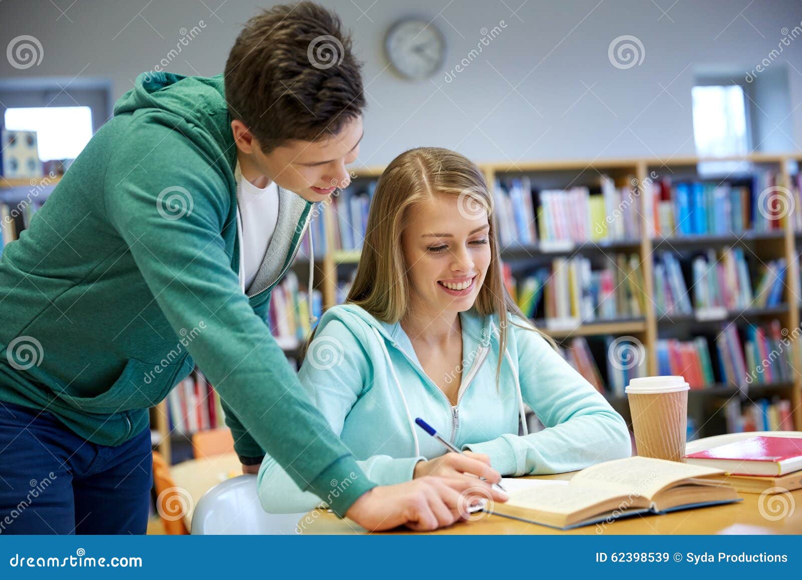 Studenti felici che preparano agli esami in biblioteca. La gente, conoscenza, istruzione e concetto della scuola - studenti felici con il libro che prepara agli esami in biblioteca