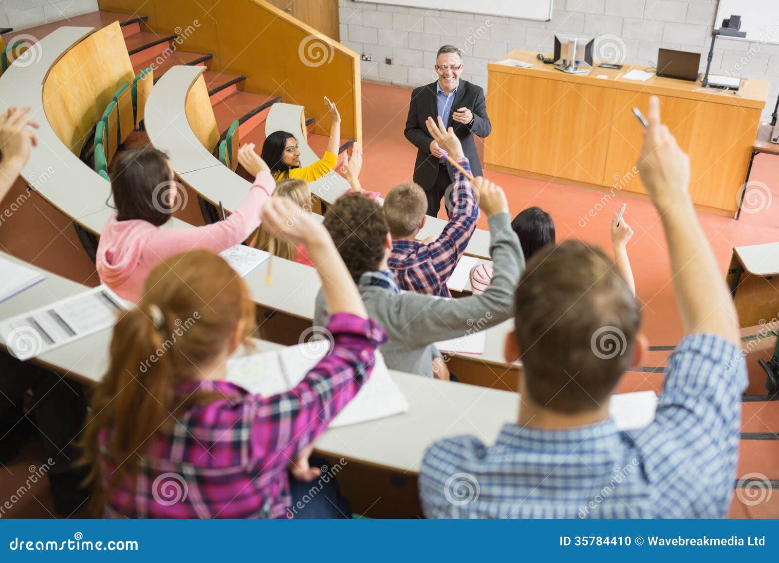 students raising hands with teacher in the lecture hall