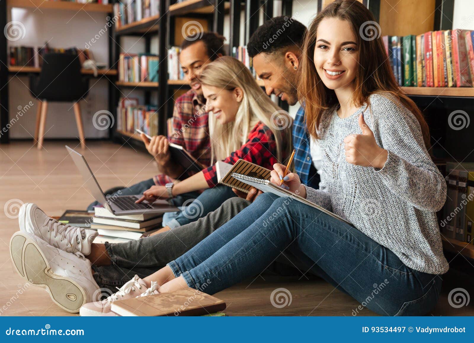 Students Sitting in Library on Floor Showing Thumbs Up