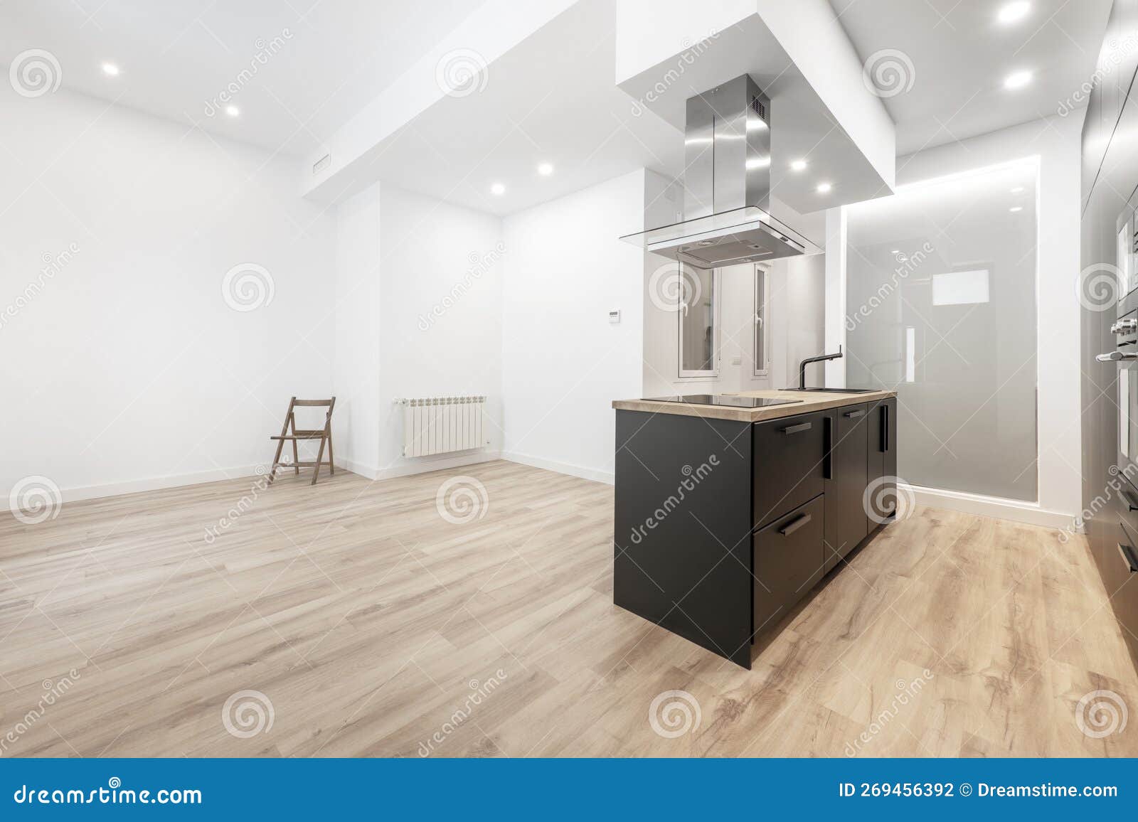 studio apartment with an open kitchen with an island with black furniture, a wooden worktop with a sink and a ceramic hob under