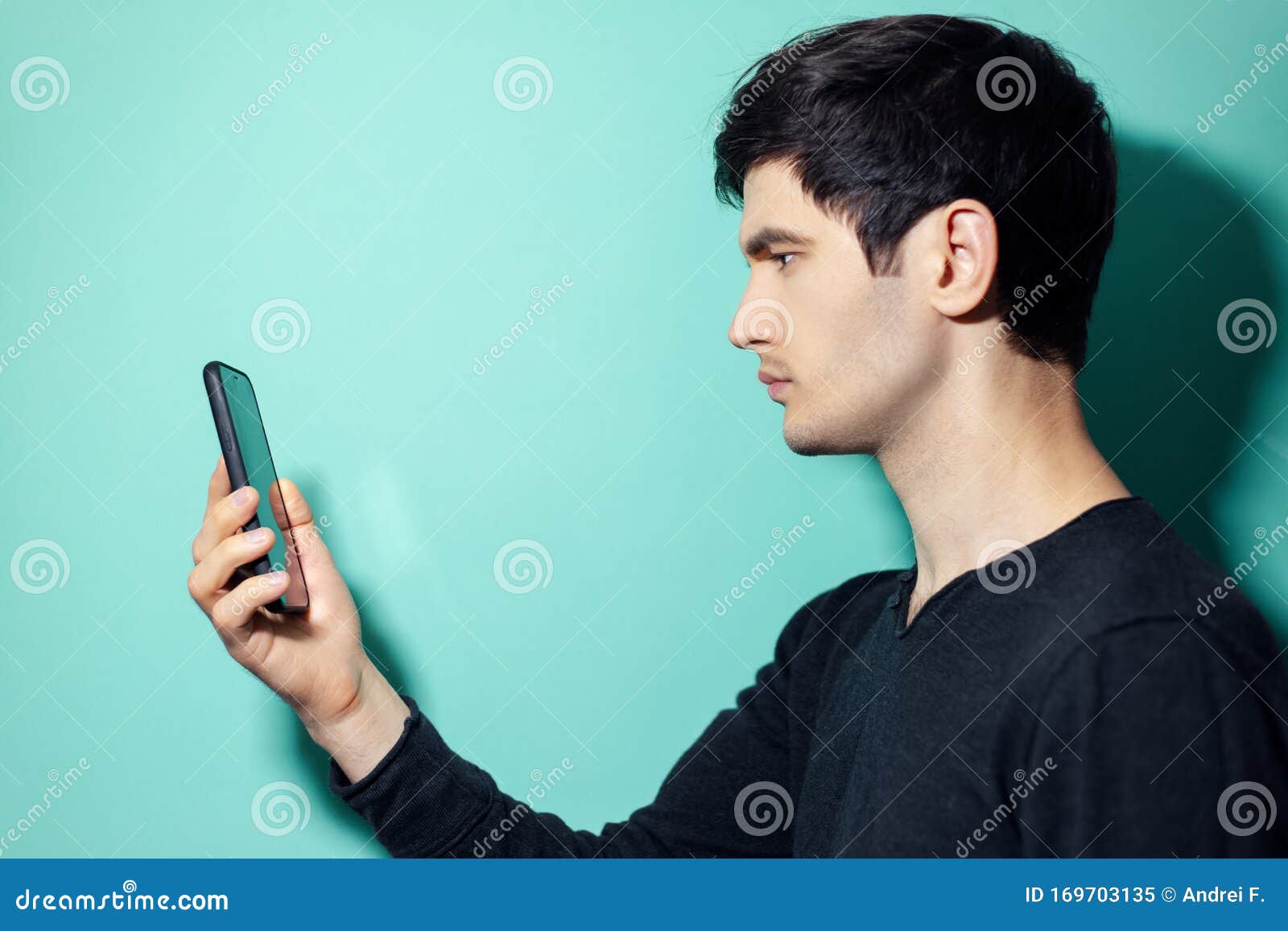 Studio Profile Portrait of Young Guy Looking in Smartphone on ...