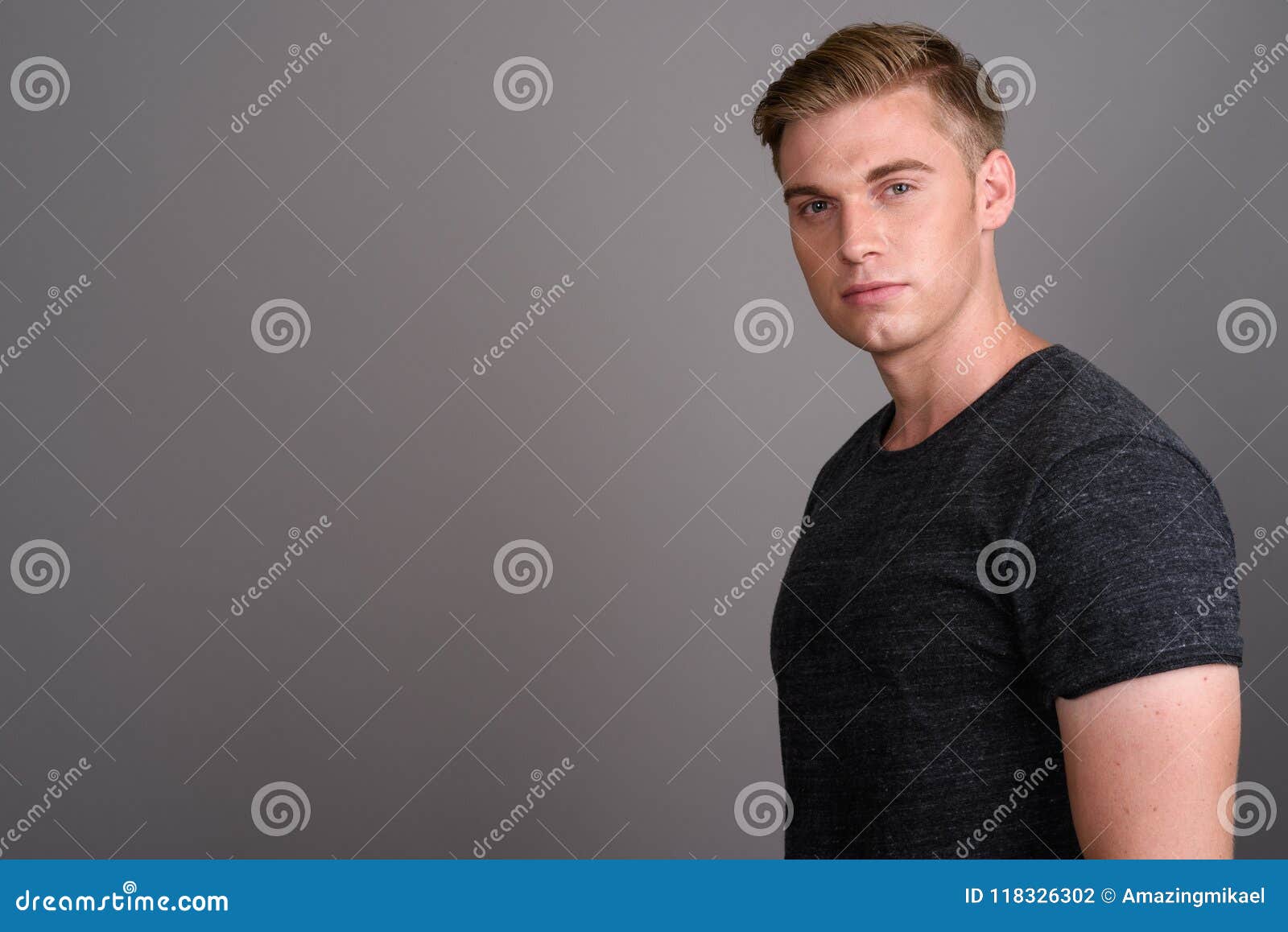 Young Handsome Man With Blond Hair Wearing Gray Shirt Against Gr