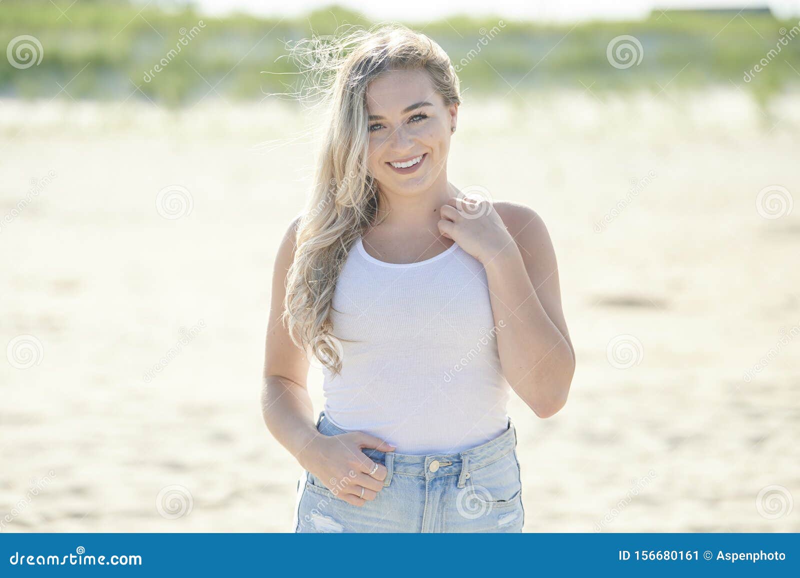 Premium Photo | A beautiful young brunette woman in jeans walks along a  picturesque sandy beach