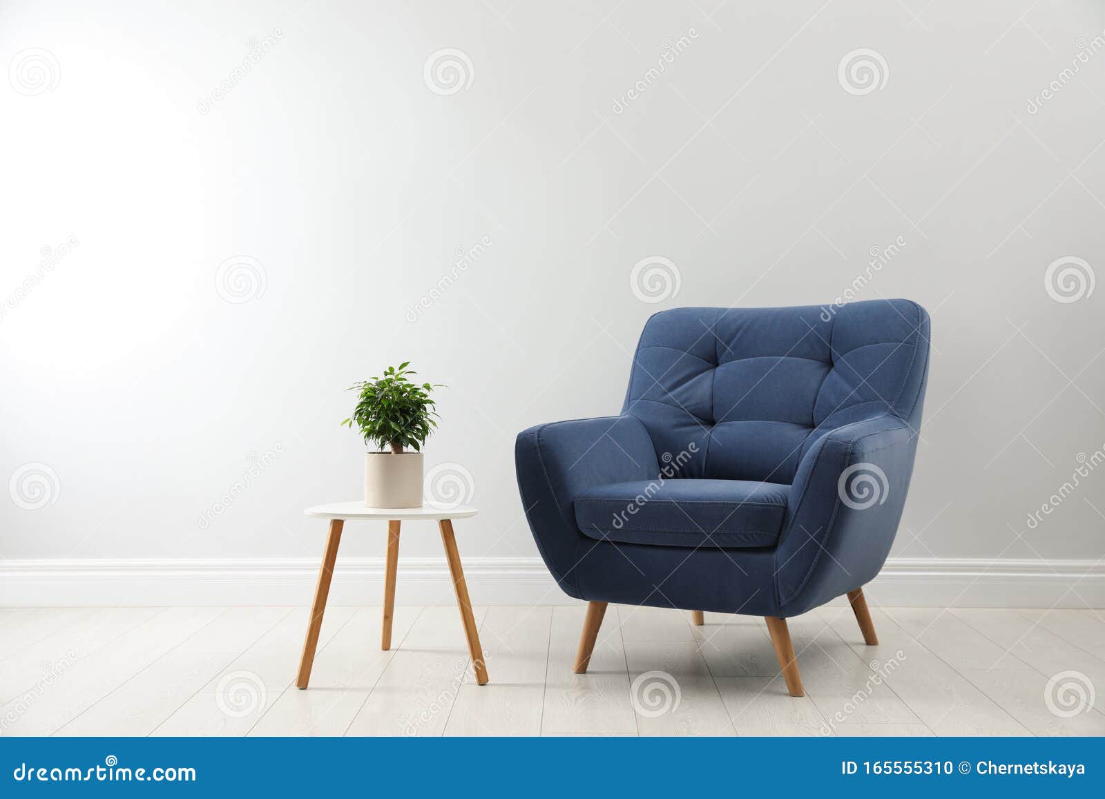 stylish armchair and table with houseplant near wall. interior 