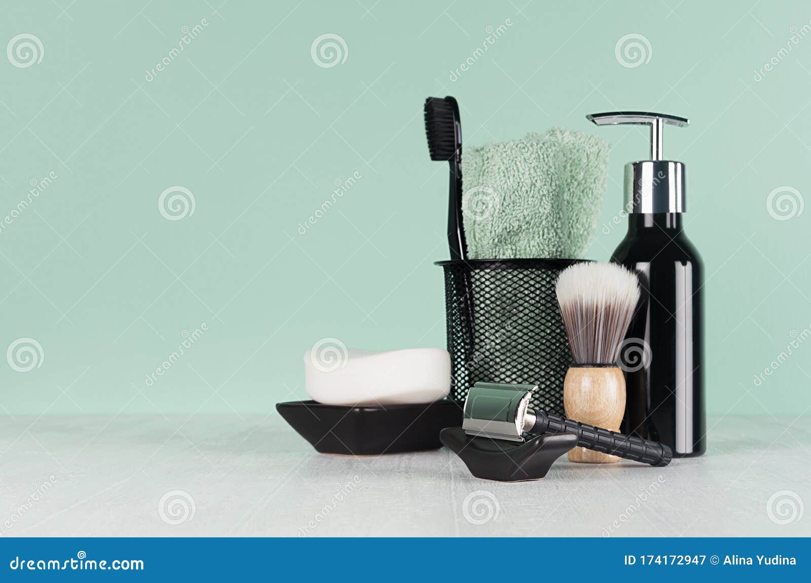 stylish bathroom interior with black shaving accessories on green  wall, white table - razor, toothbrush, towel, soap, shave brush