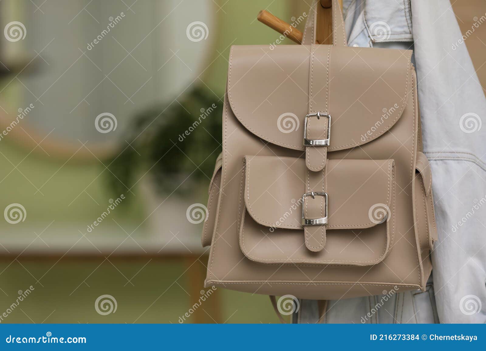 Stylish Beige Backpack and Jacket Hanging on Clothes Rack Indoors