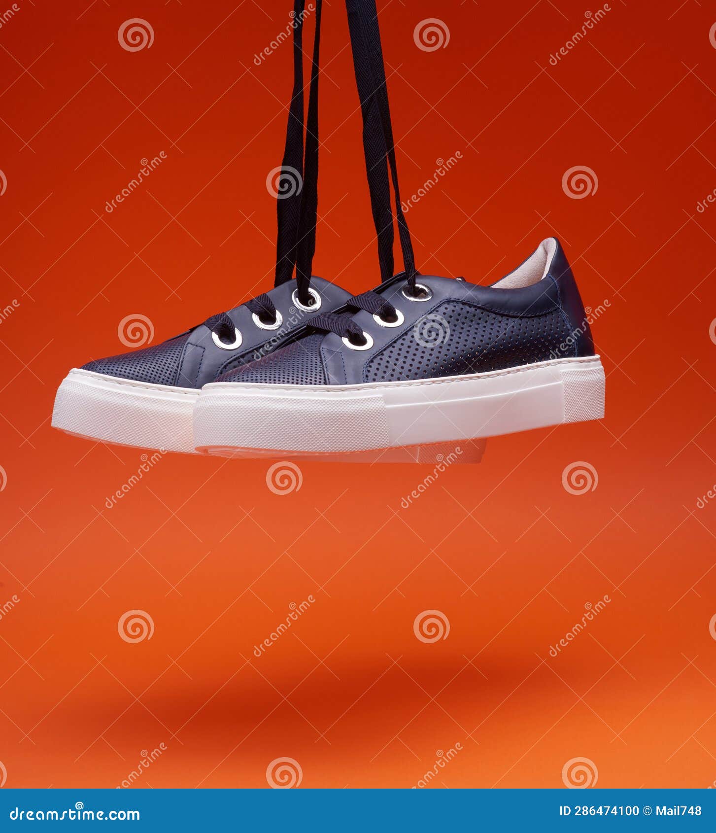 Stylish Casual Navy Blue Sneakers Hanging in Front of a Bright Orange ...