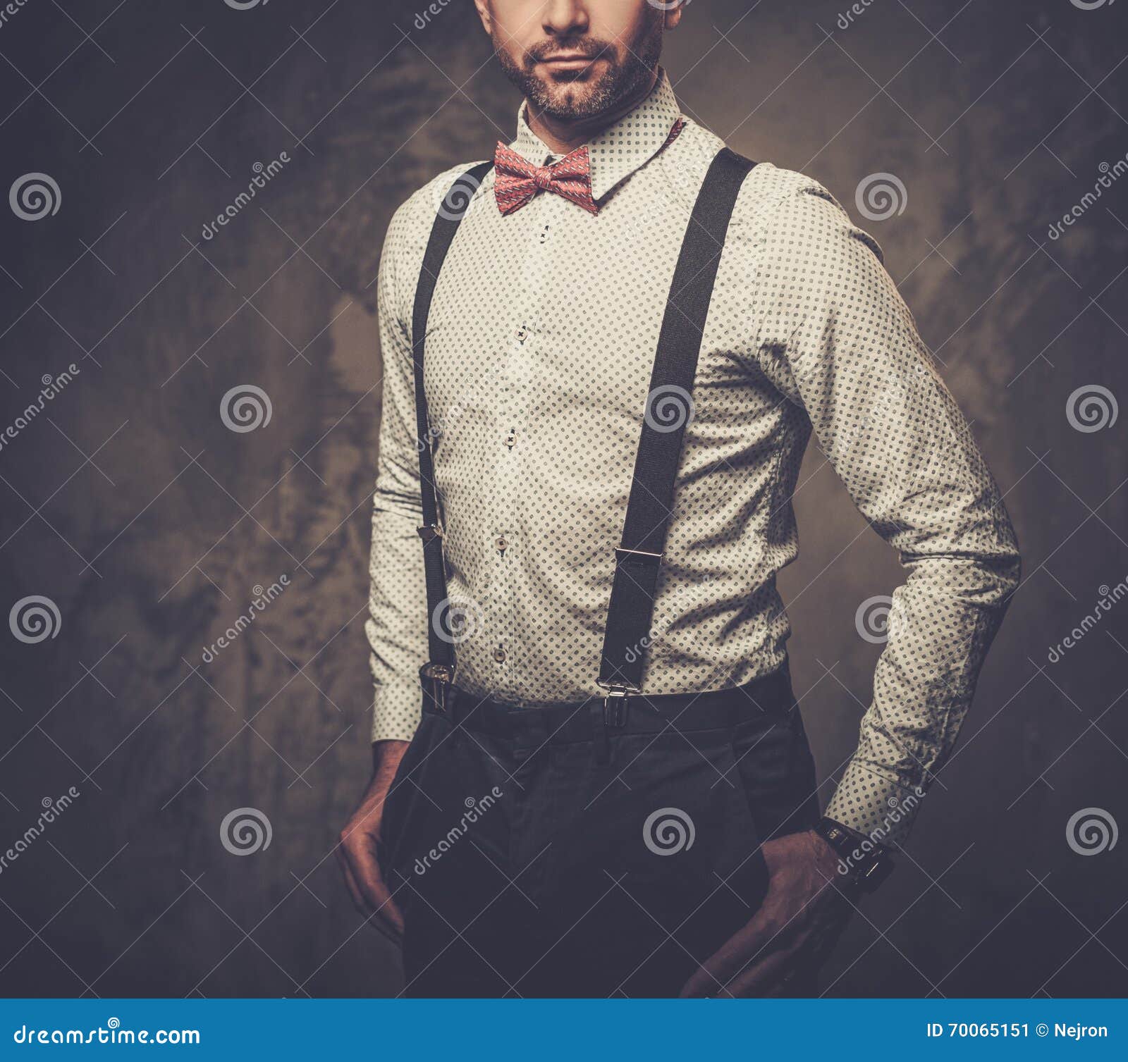 Stylish Man With Bow Tie Wearing Suspenders And Posing On Dark ...