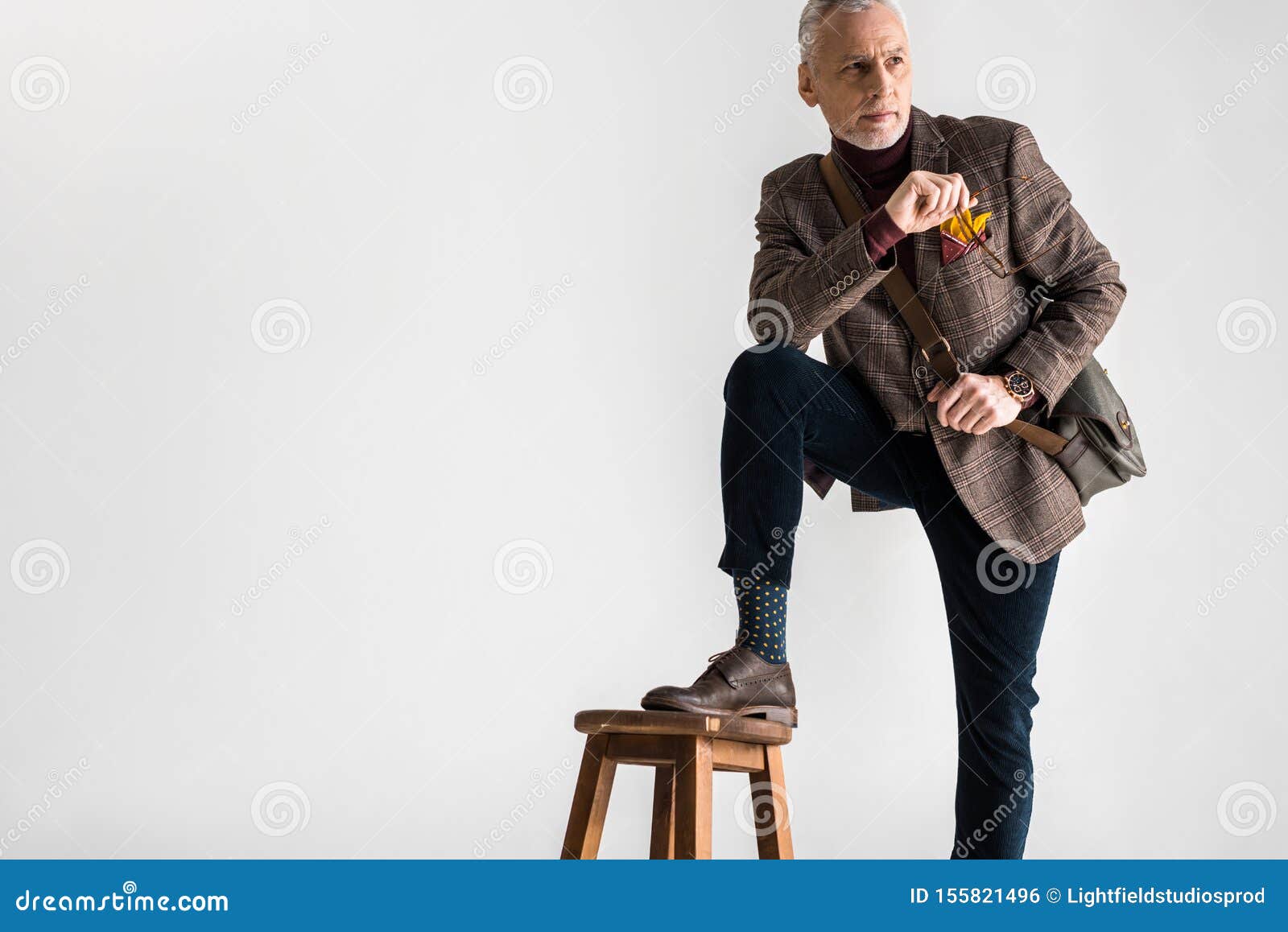Stylish Mature Man Putting Leg On Chair While Standing And Holding