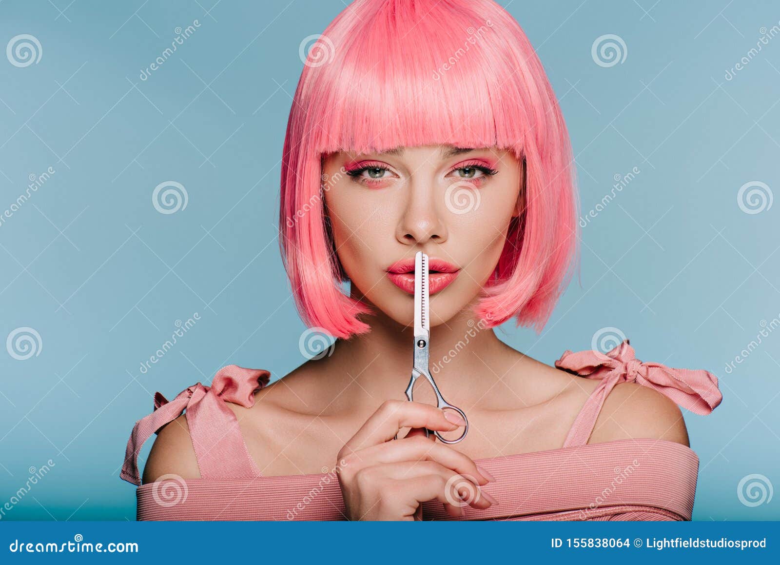 stylish sensual girl in pink wig showing silence  with scissors 