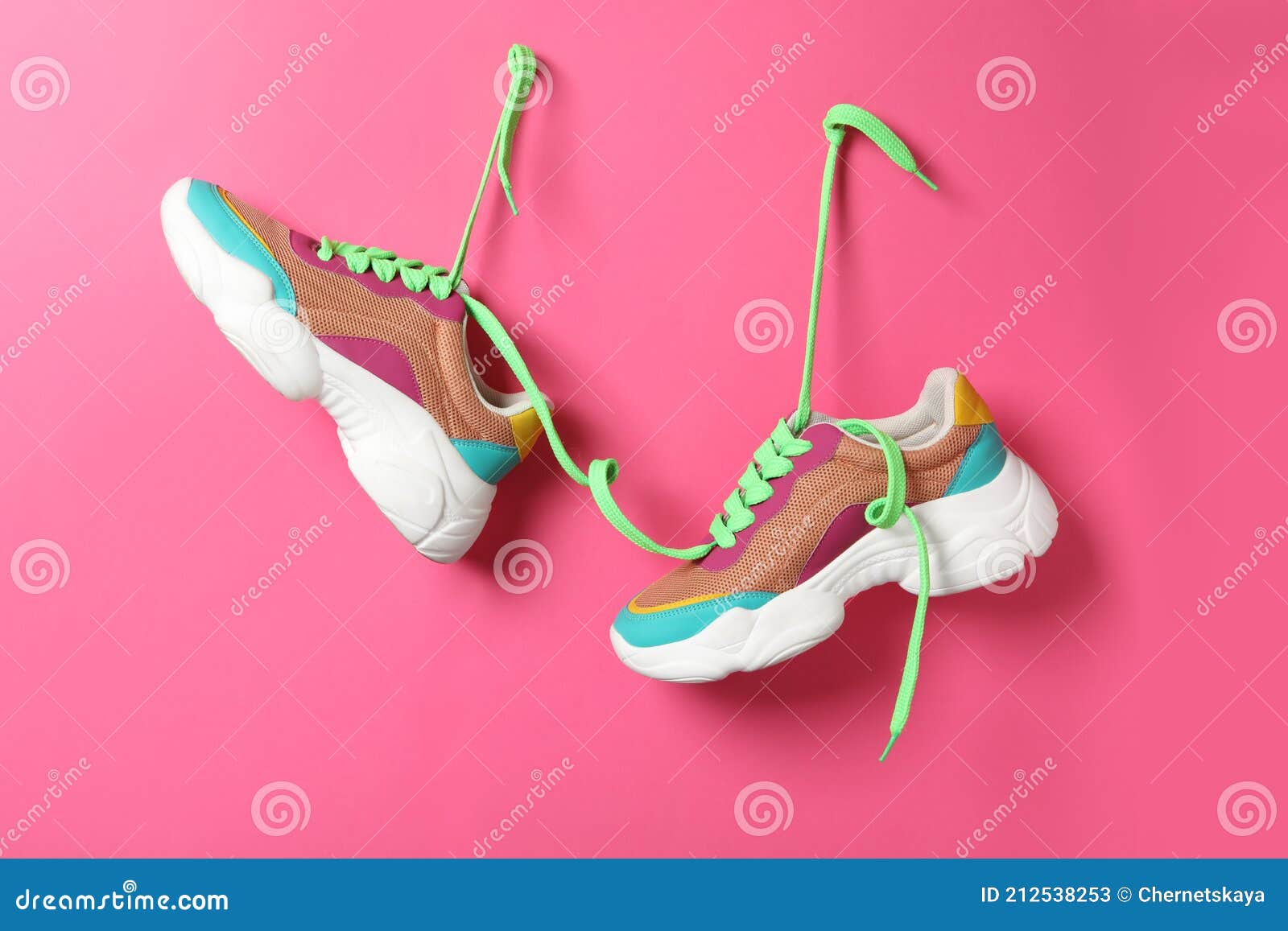 Stylish Sneakers with Green Shoe Laces Hanging on Pink Wall Stock Image ...