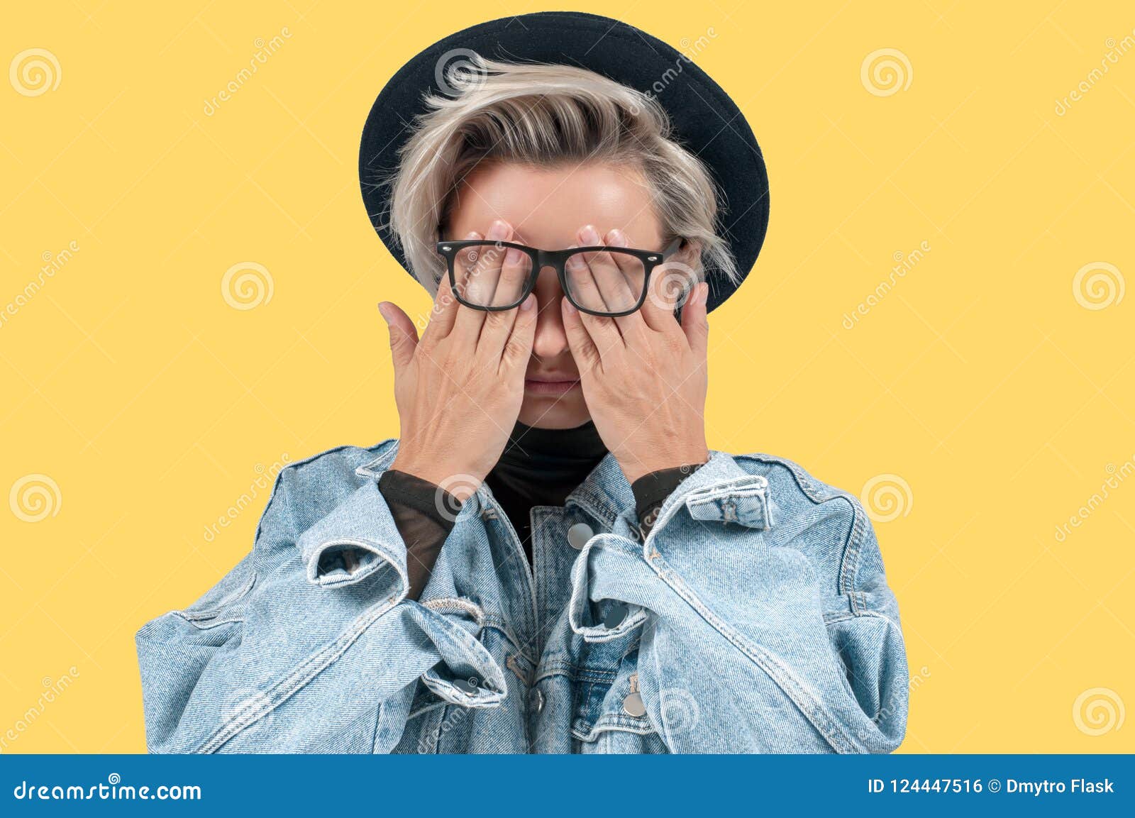 Stylish Woman Closes Eyes with Her Hands in Jeans Jacket and Hat on ...