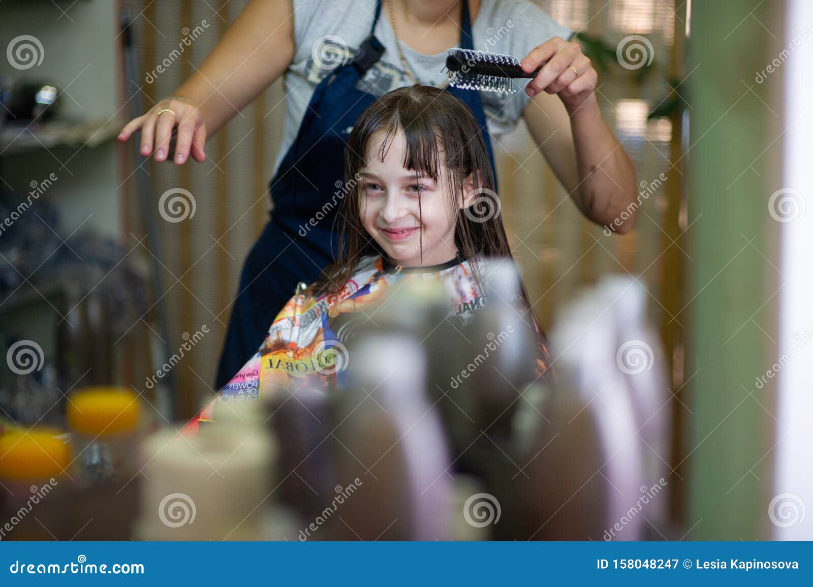 Stylist Hairdresser Makes A Hairstyle For A Cute Little Girl In A