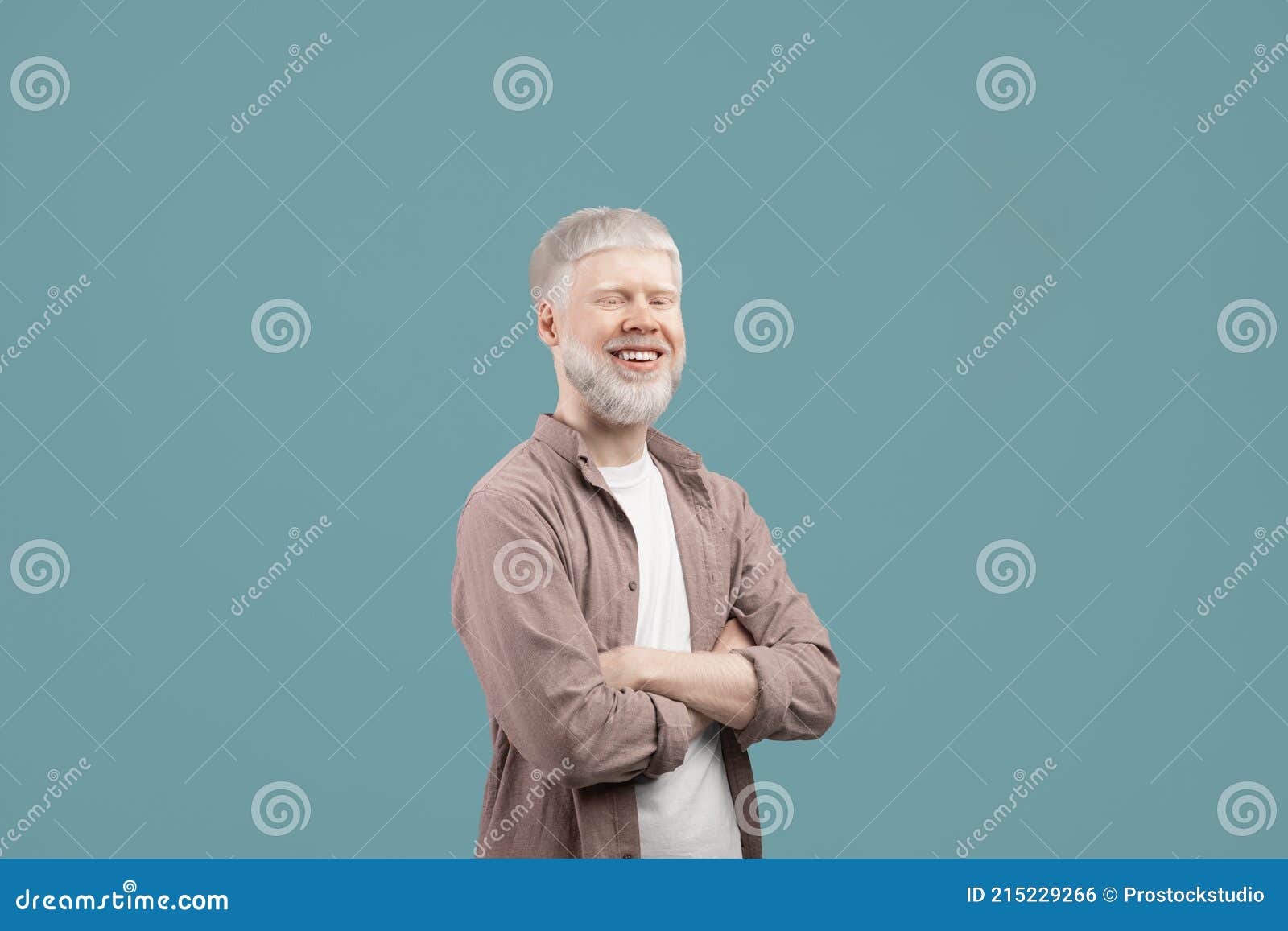 successful albino man posing with crossed arms, wearing casual clothes and smiling to camera over turquoise background