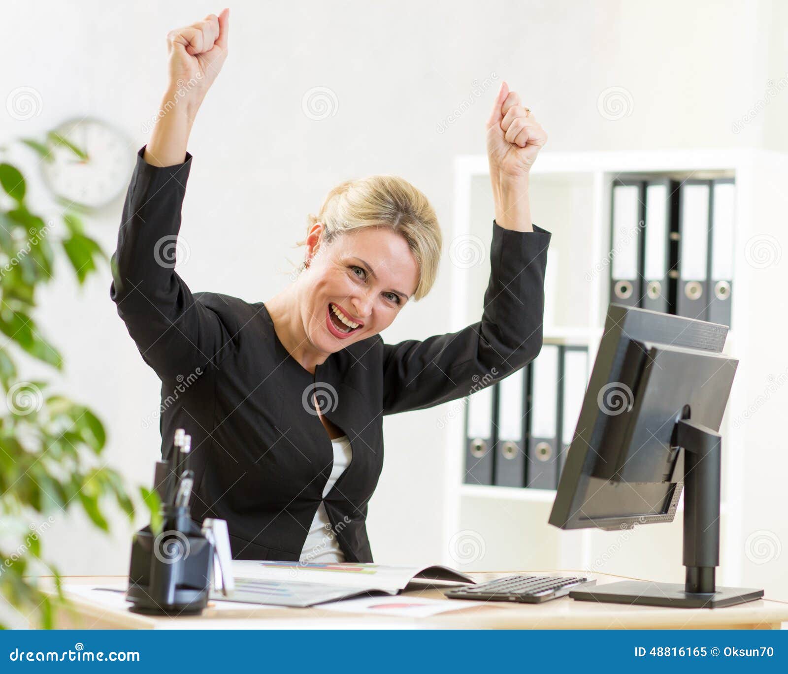 successful business woman with arms up in office