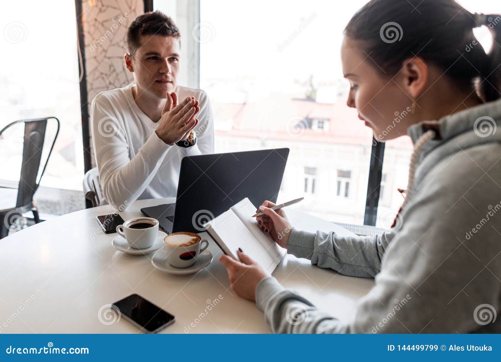 successful leader and business owner leads an informal business meeting in a cafe.young woman takes notes on a notepad