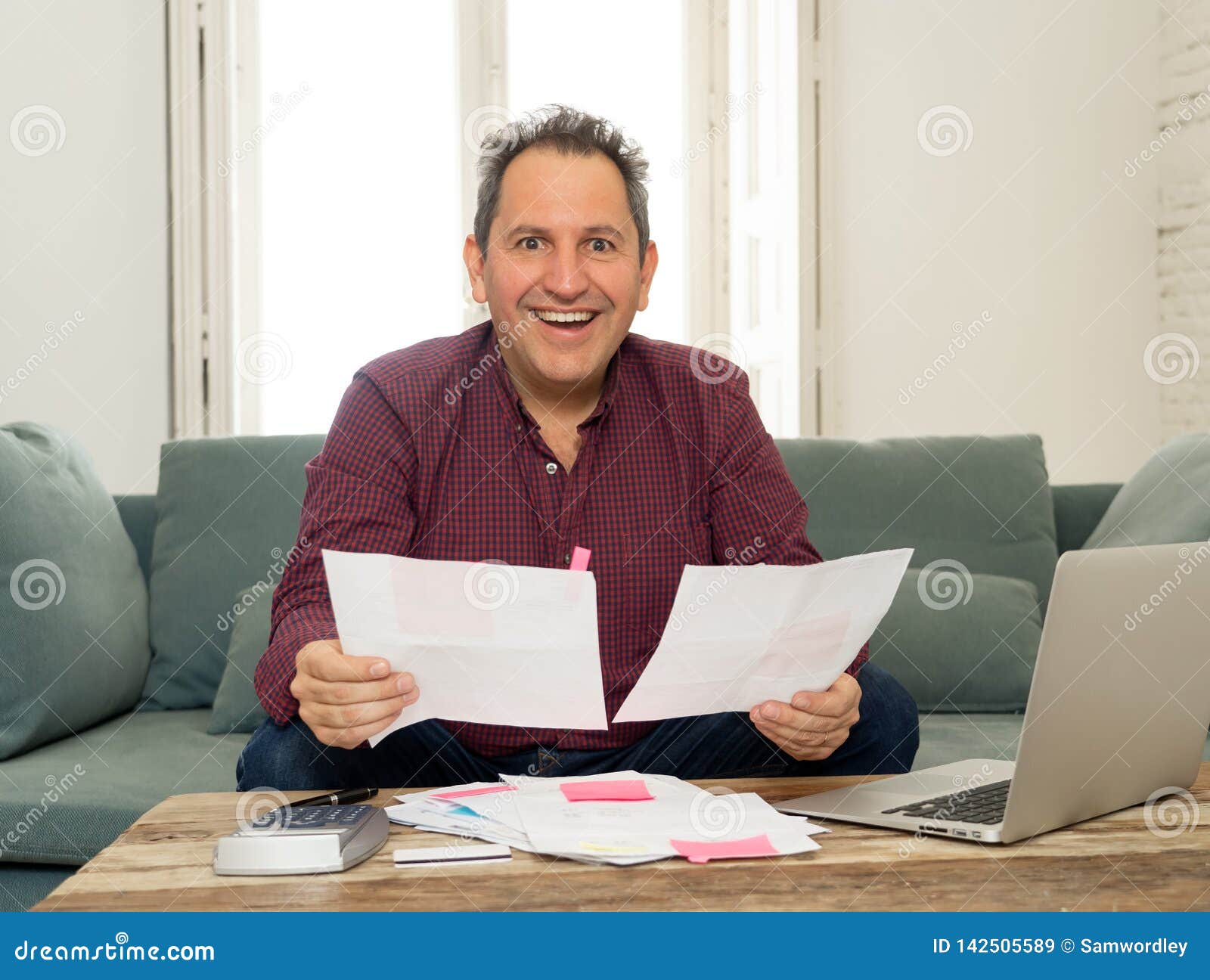 successful middle aged man with payslips, invoices and computer accounting finance happy free of debts