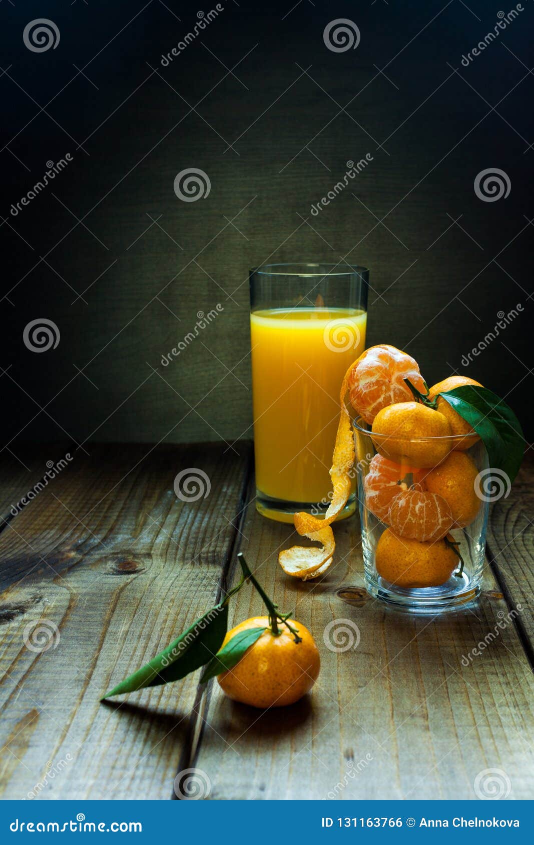 Suco de laranja e tangerinas. Vidro do suco de laranja e das tangerinas com as folhas no fundo de madeira rústico Ainda vida com espaço para o texto