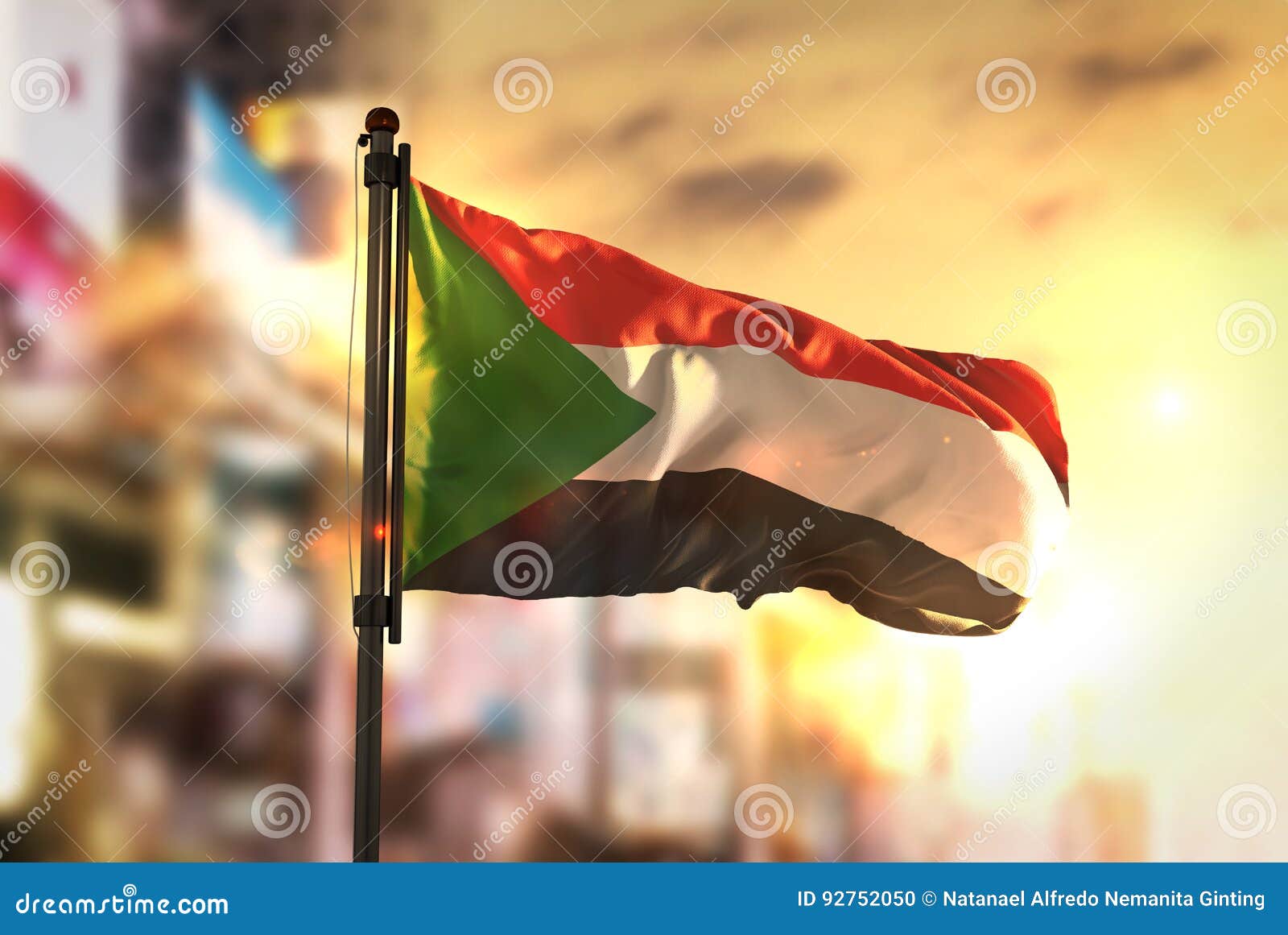 sudan flag against city blurred background at sunrise backlight