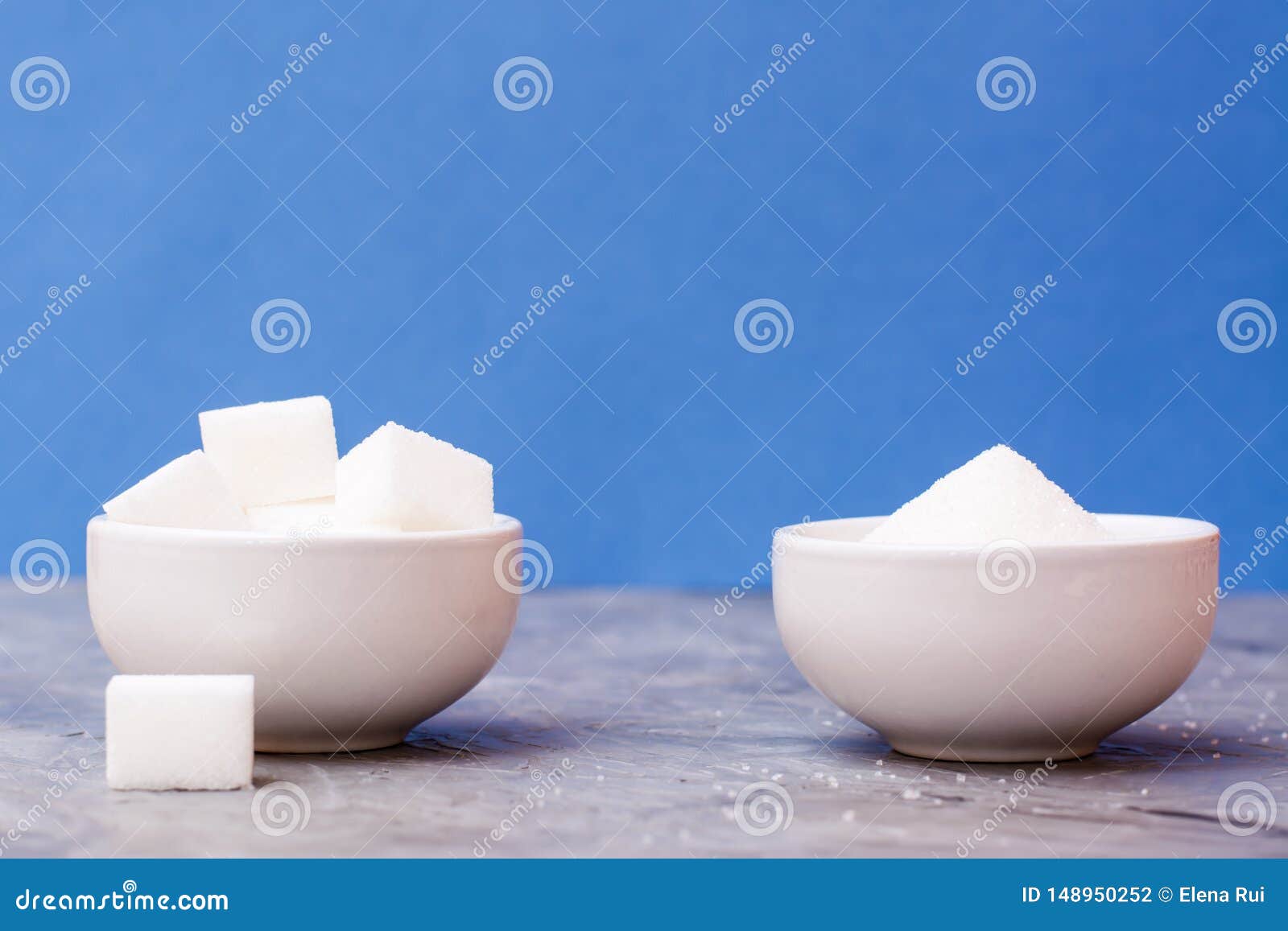 Sugar Cubes and Granulated Sugar in White Bowls on a Table Against a