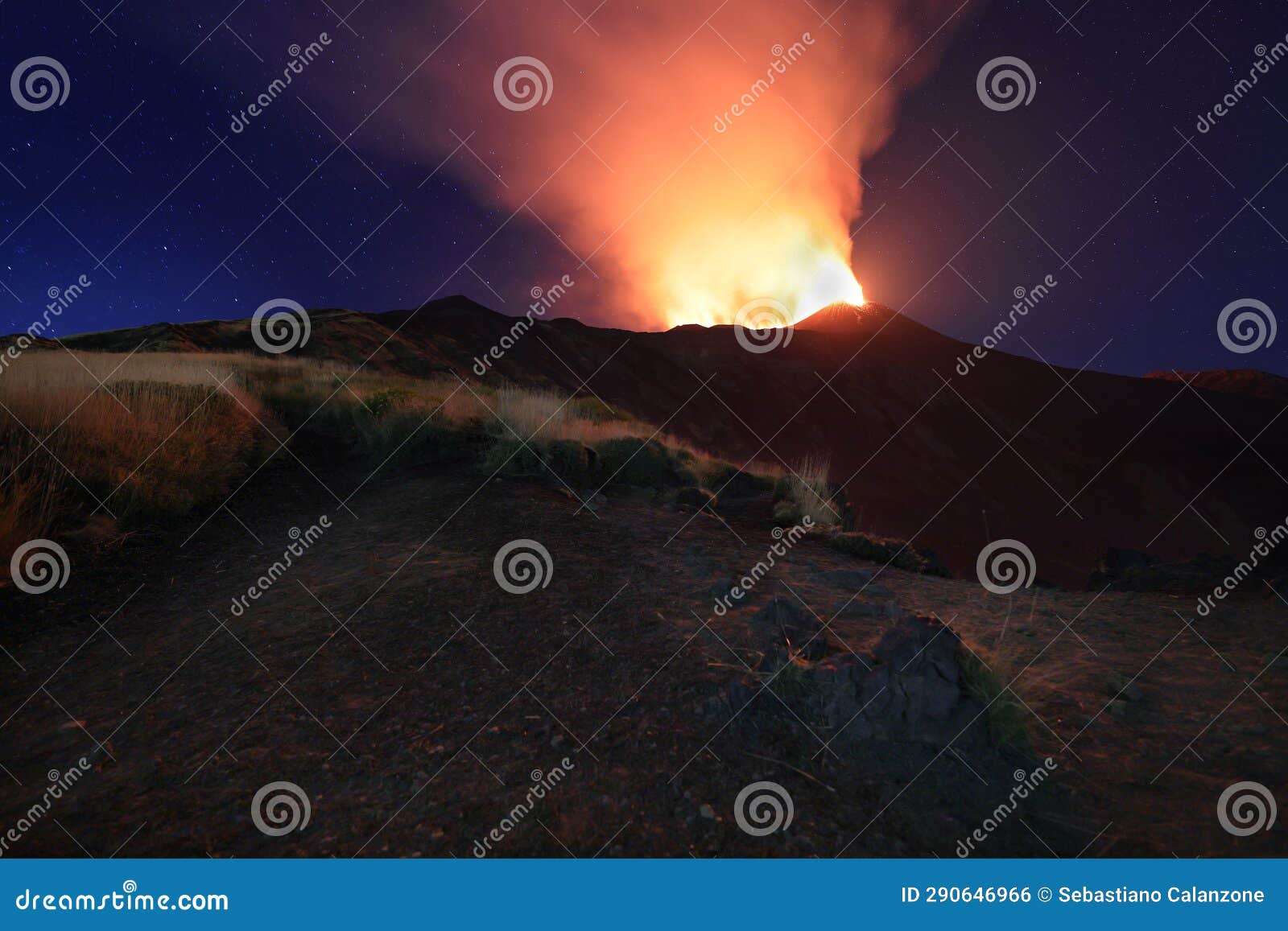 suggestiva eruzione del vulcano etna con esplosione di lava dalla cima del cratere con sfondo il cielo stellato e paesaggio