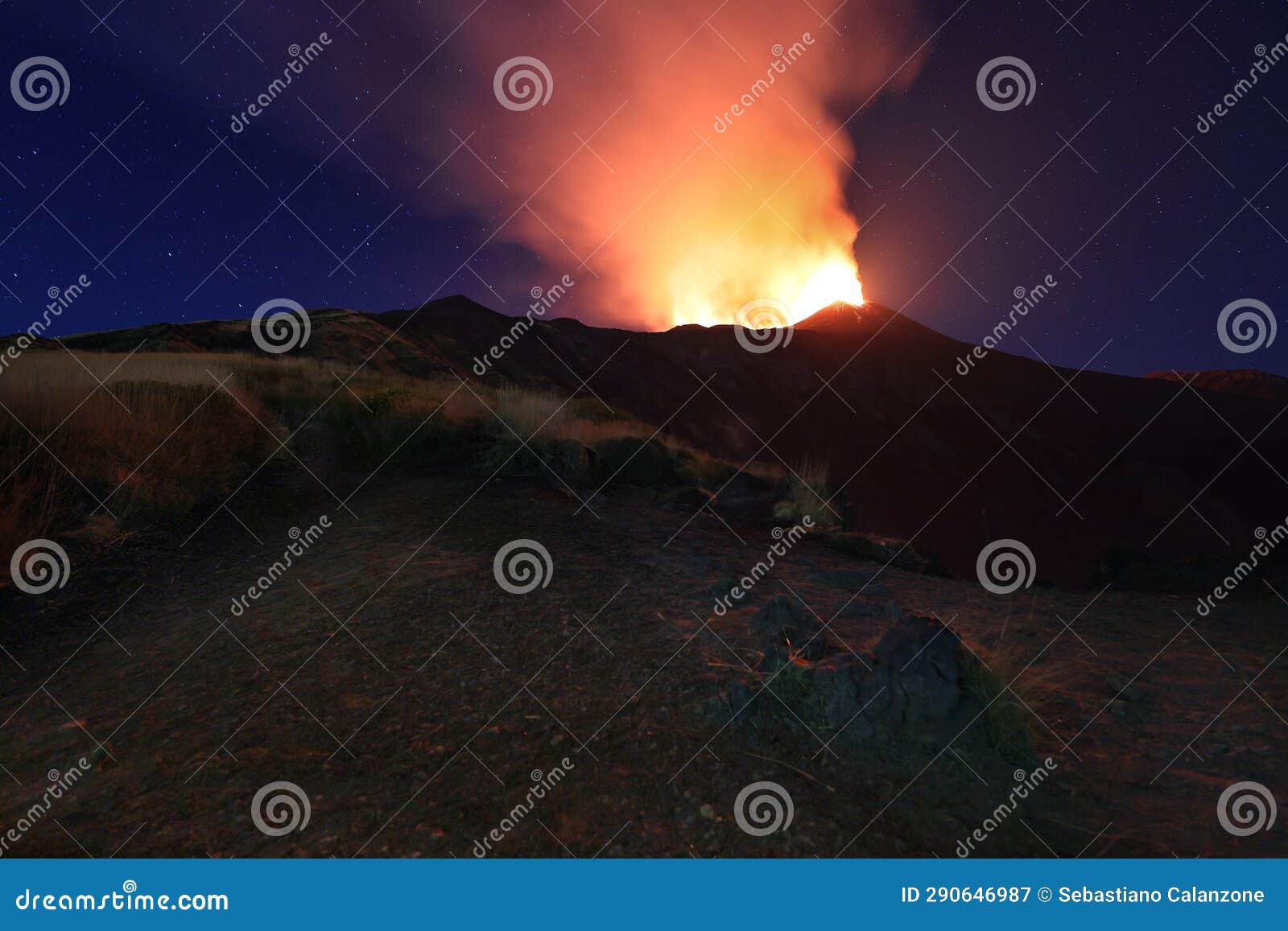 suggestiva eruzione del vulcano etna con esplosione di lava dalla cima del cratere con sfondo il cielo stellato e paesaggio