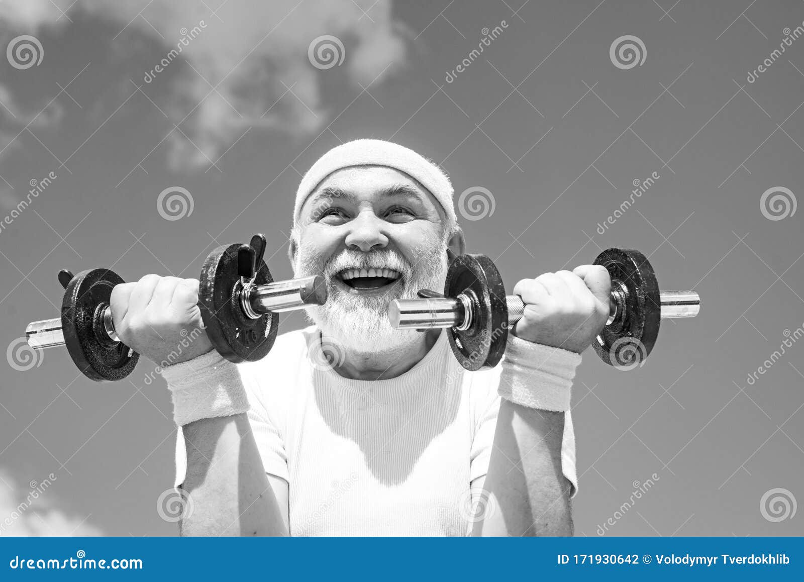 Summer and active holidays. Happy Grandfather sportsman portrait on blue sky backgrounds. Healthcare cheerful lifestyle. Senior sportman lifting dumbbells. Elderly man workout