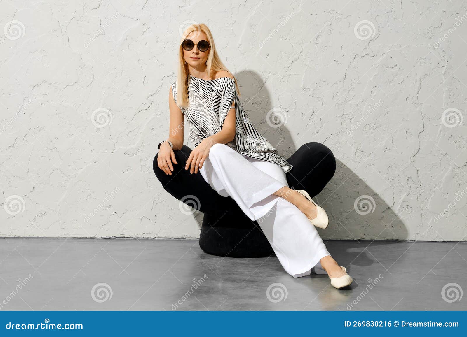 Blonde Woman In Blouse And Wide Trousers Throw Her Leg On Another Leg