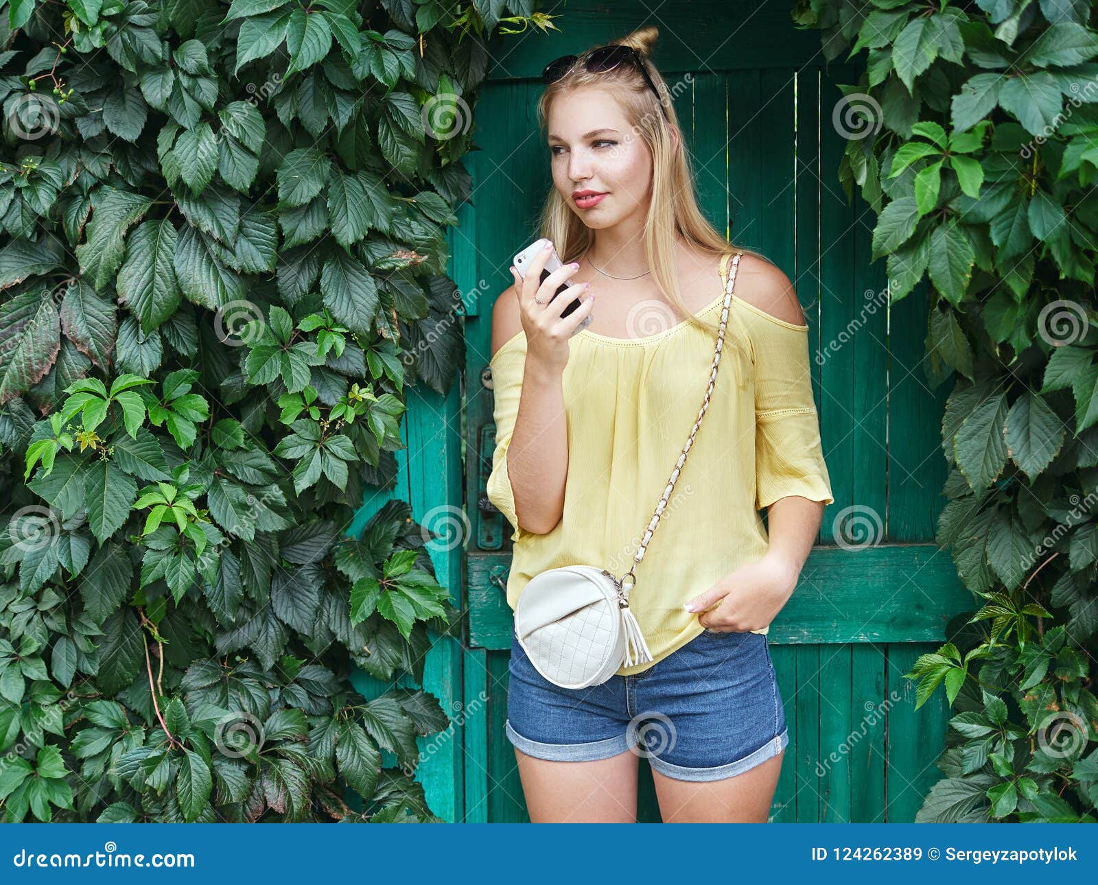 Outdoors Portrait Of Young Beautiful Blonde Woman With High Bun Hairstyle  Jeans Shorts Yellow Blouse Enjoying Journey Weekend Posi Stock Photo  124262389 - Megapixl