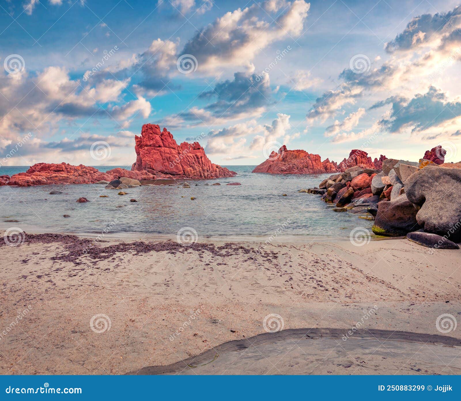 summer scene of cea beach with red rocks gli scogli rossi - faraglioni on background.