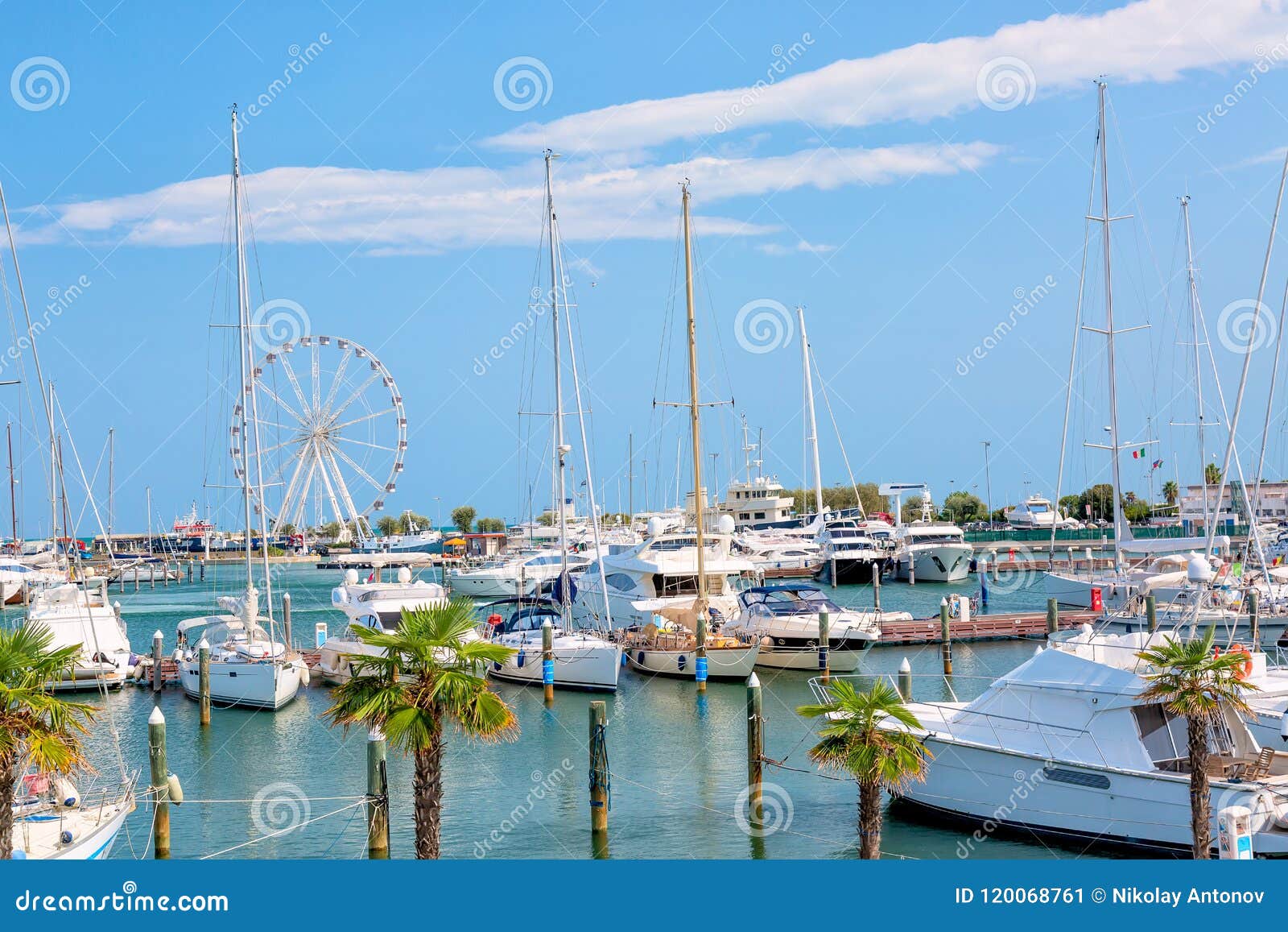 summer view of pier with ships, yachts and other boats with ferris wheel in rimini, italy