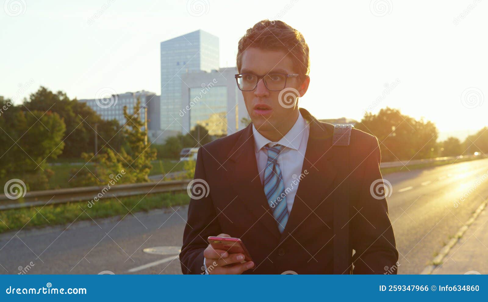 sun flare: stressed yuppie looks around the city as he walks home at sunset.