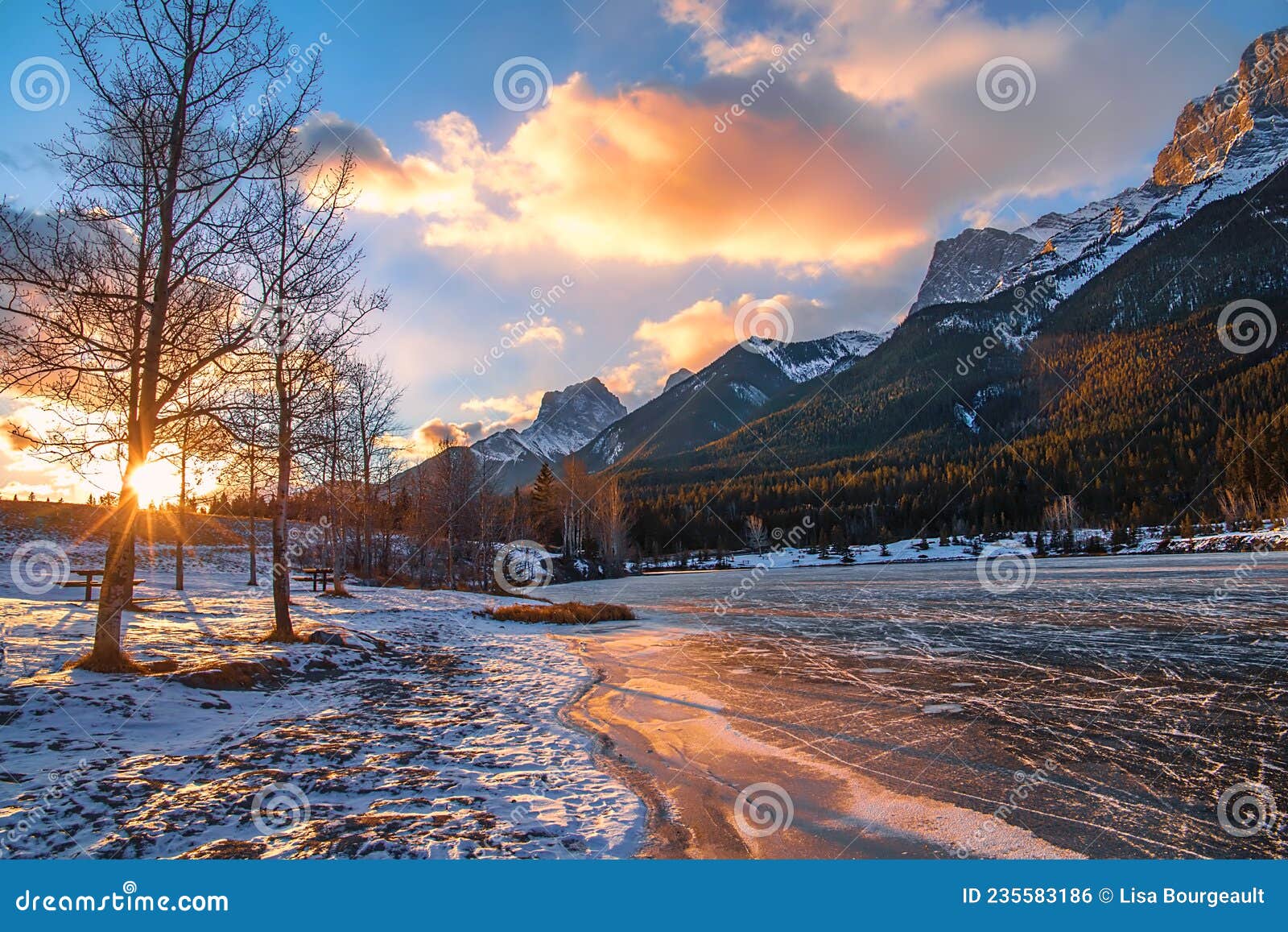 sun glowing over a frozen mountain park lake