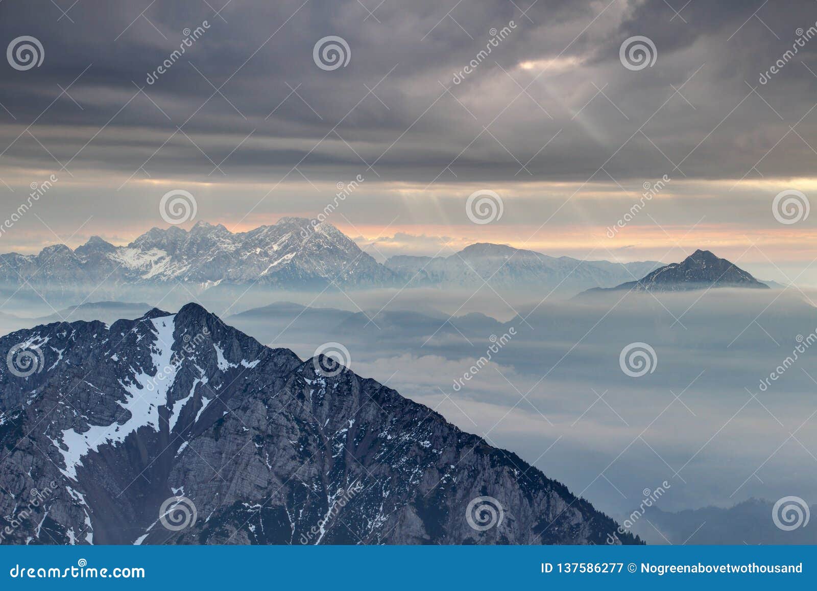 sun rays burst through dark clouds in karavanke and kamnik alps