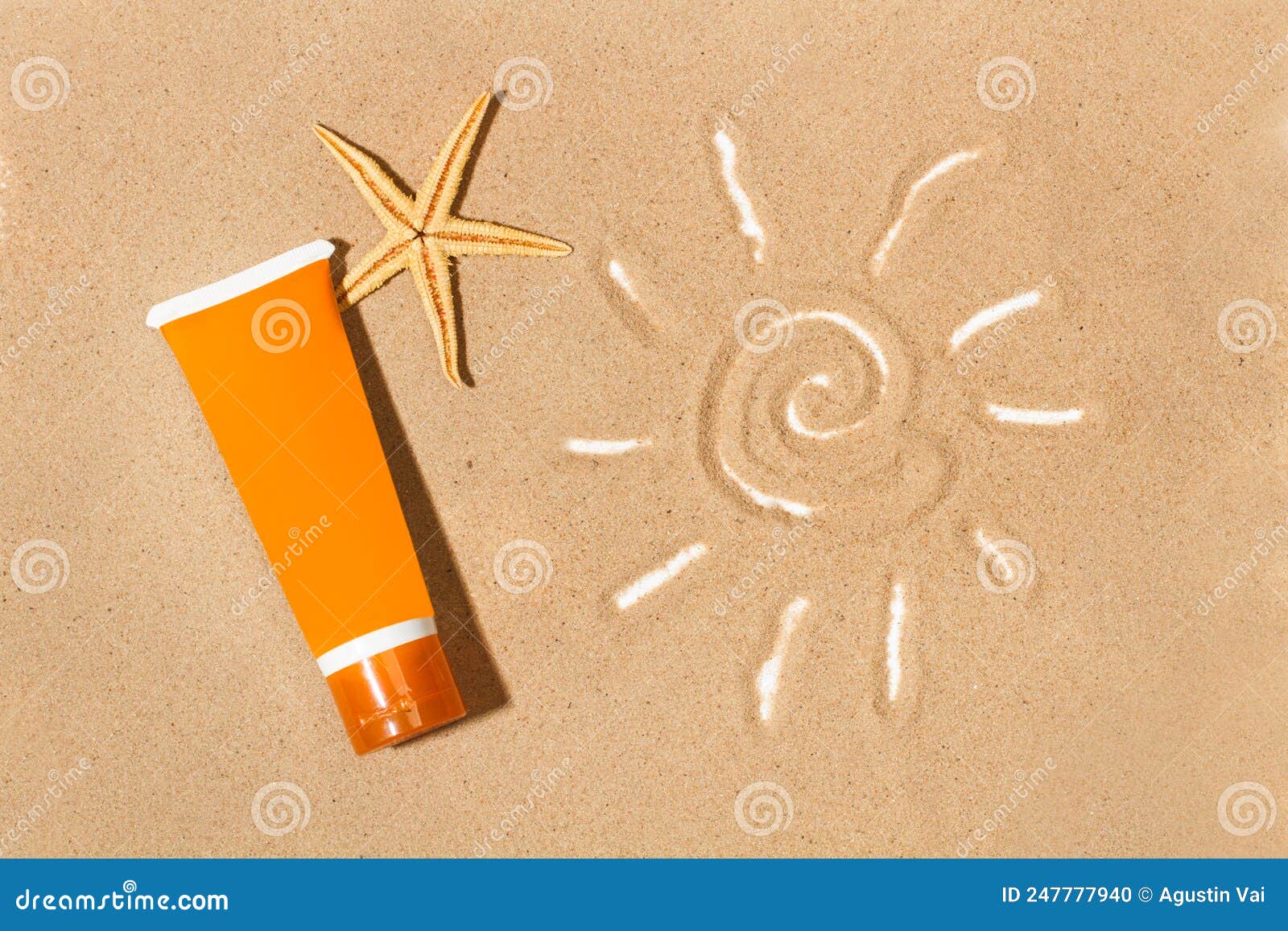 A Sun Tan Lotion and a Drawing of the Sun on the Sand Stock Photo