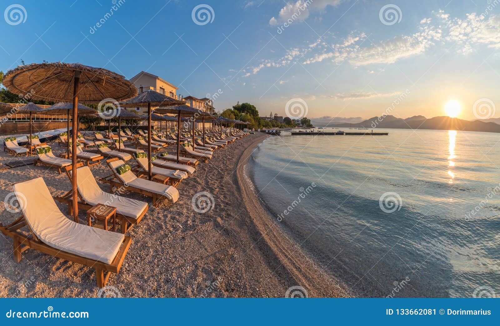 sunbeds and umbrella on the beach at sunset time, corfu island, greece