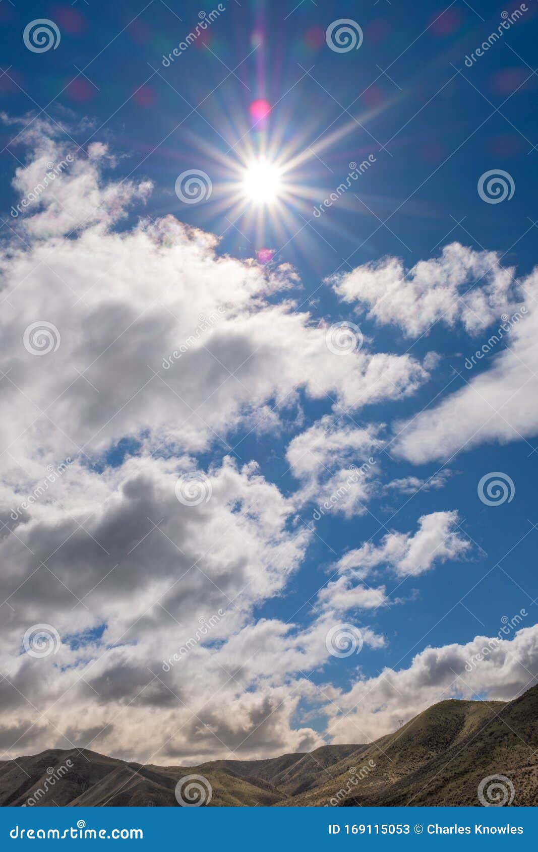 Sunburst in a Sky Surrounded with White Puffy Clouds Stock Image