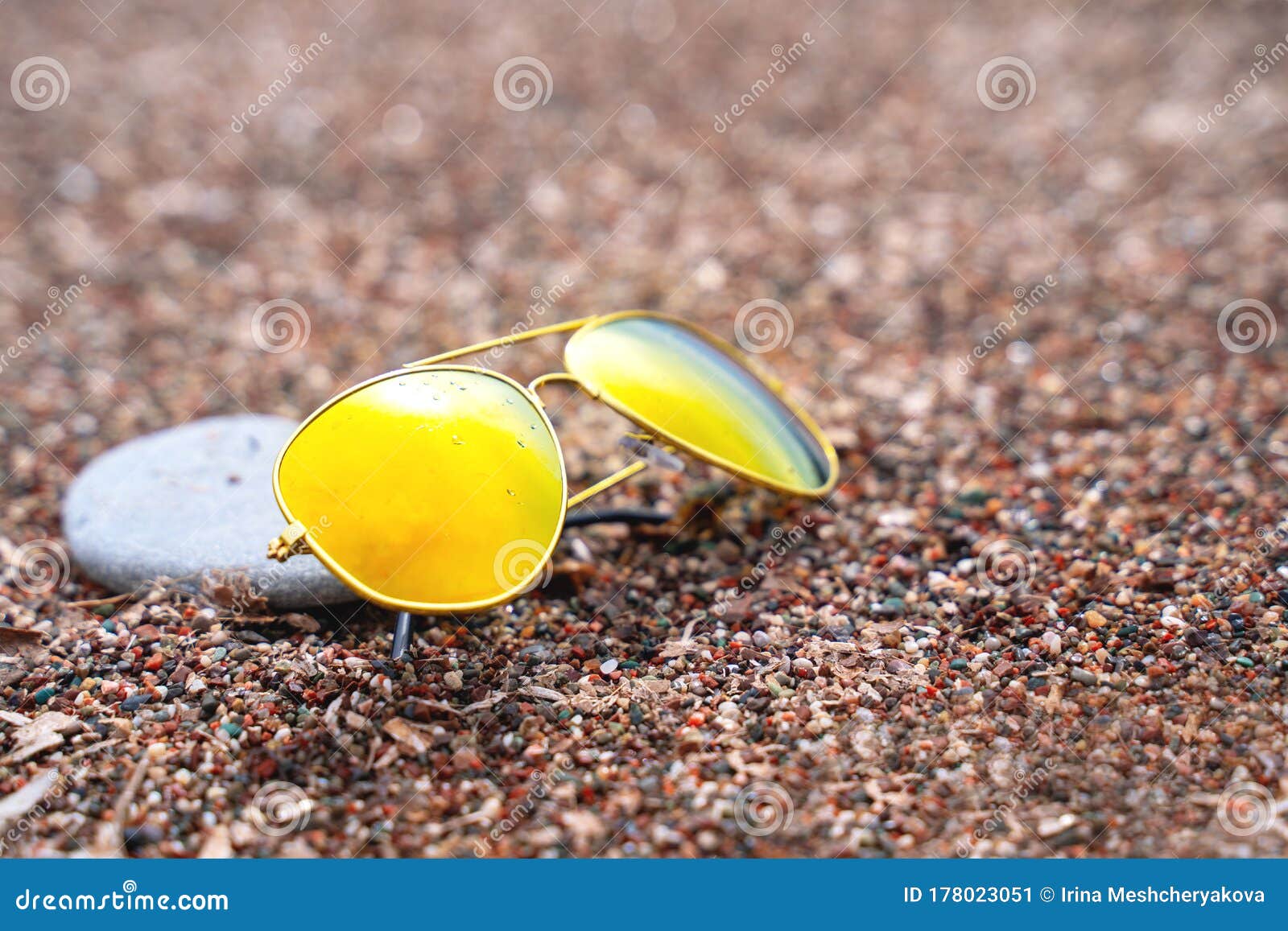 Sunglasses with Polarizing Lenses with Pebble Nearby Lie on Sand, Close ...