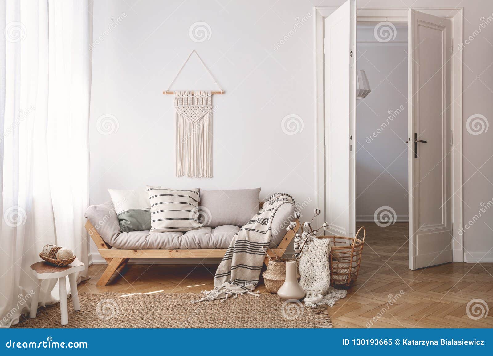 sunlit living room interior with open door, herringbone parquet floor, natural, beige textiles and white walls
