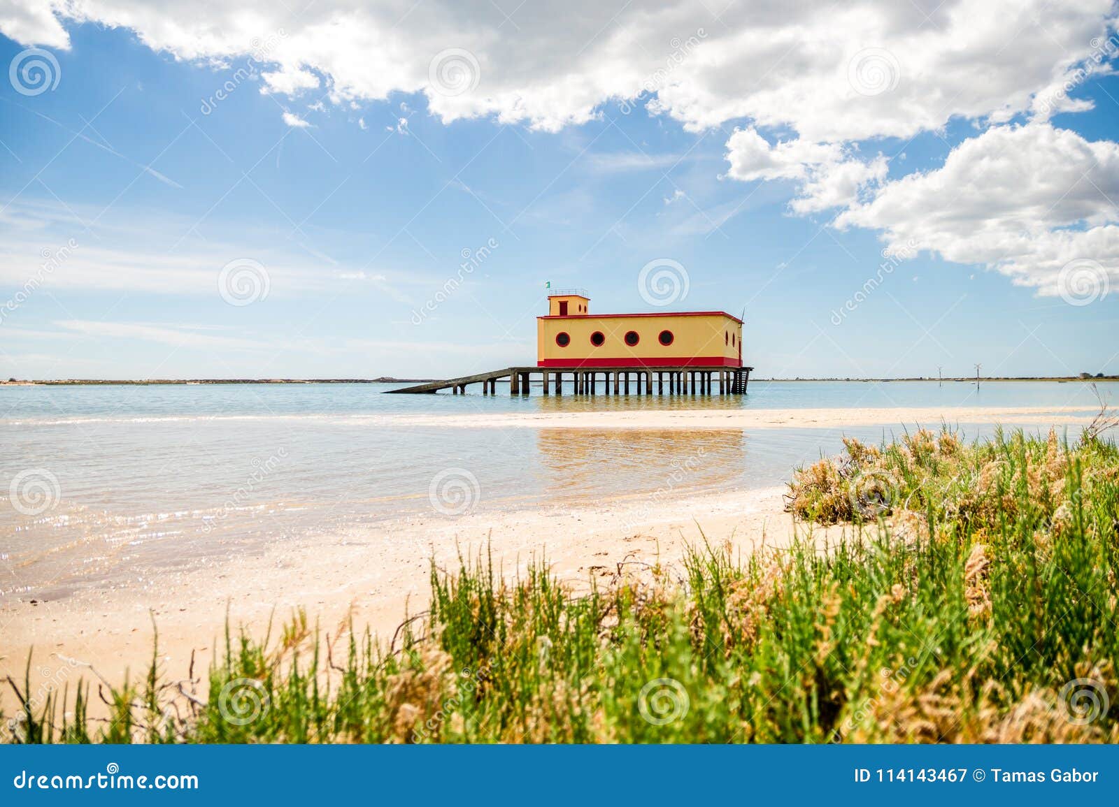 sunny beach view of the historical life-guard building in fuseta, ria formosa natural park, portugal