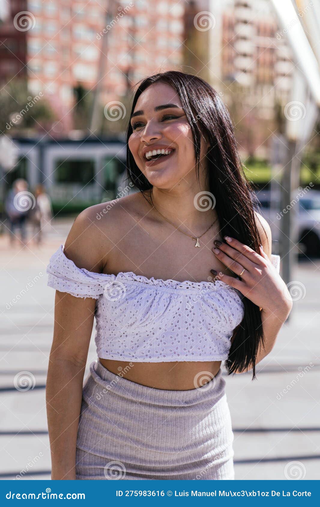 sunny street style: beautiful latina smiling in modern casual attire with tram in background