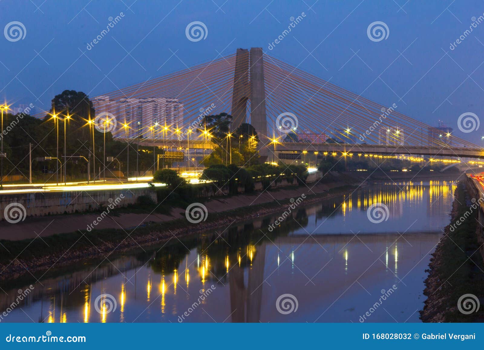 beginning of the day in metropolis, bright lights and vehicles in transit. sao paulo city highway beside the river.