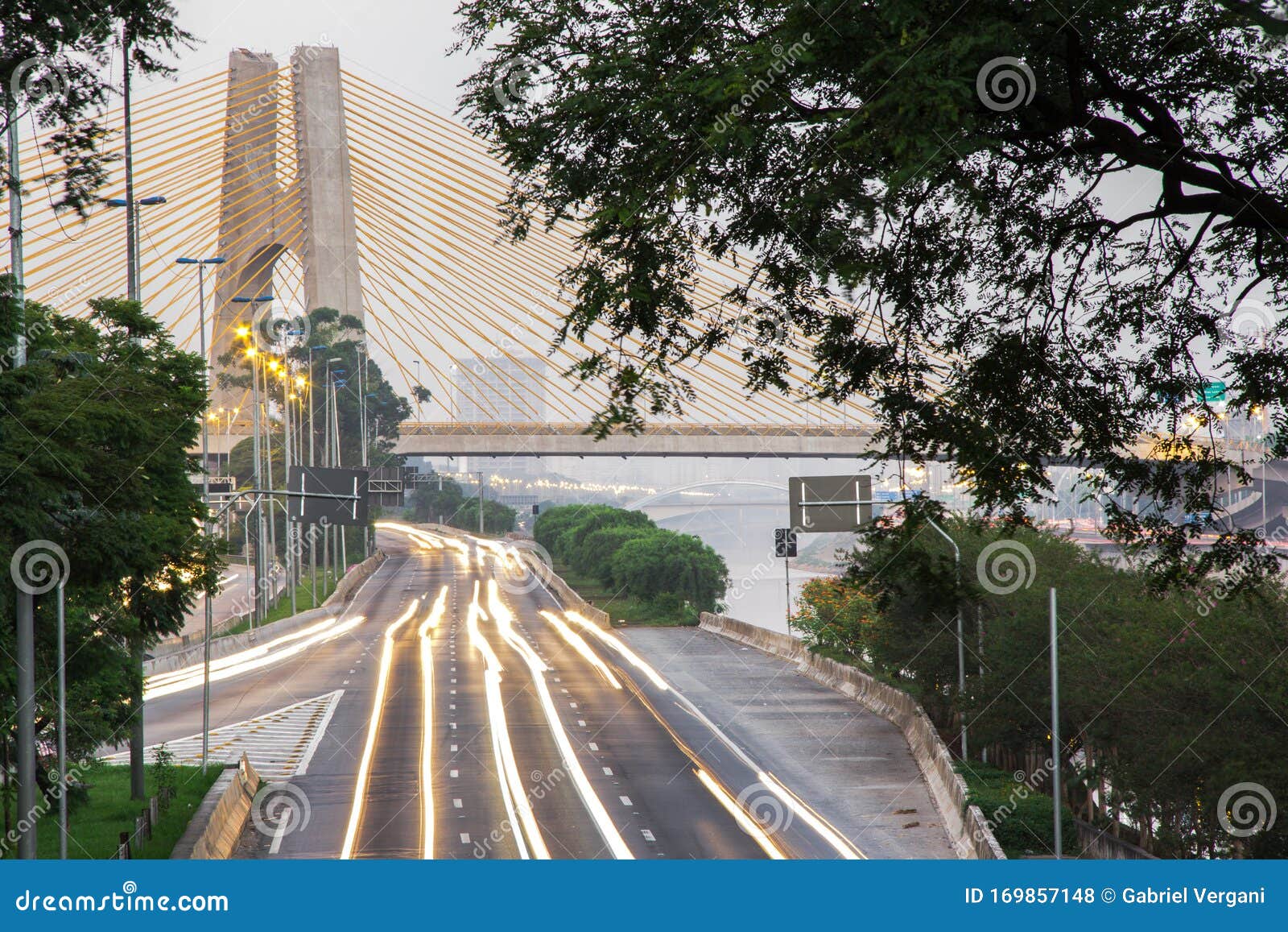 sunrise, bright lights and vehicles in transit. sao paulo city highway beside the river.